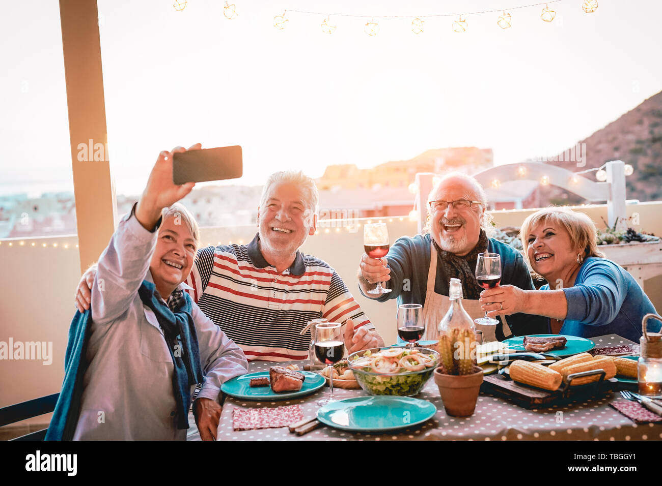 Happy Senioren Freunde unter selfie mit Mobile Smartphone kamera Barbecue Dinner - reife Menschen Spaß essen und trinken Rotwein auf der Terrasse Stockfoto