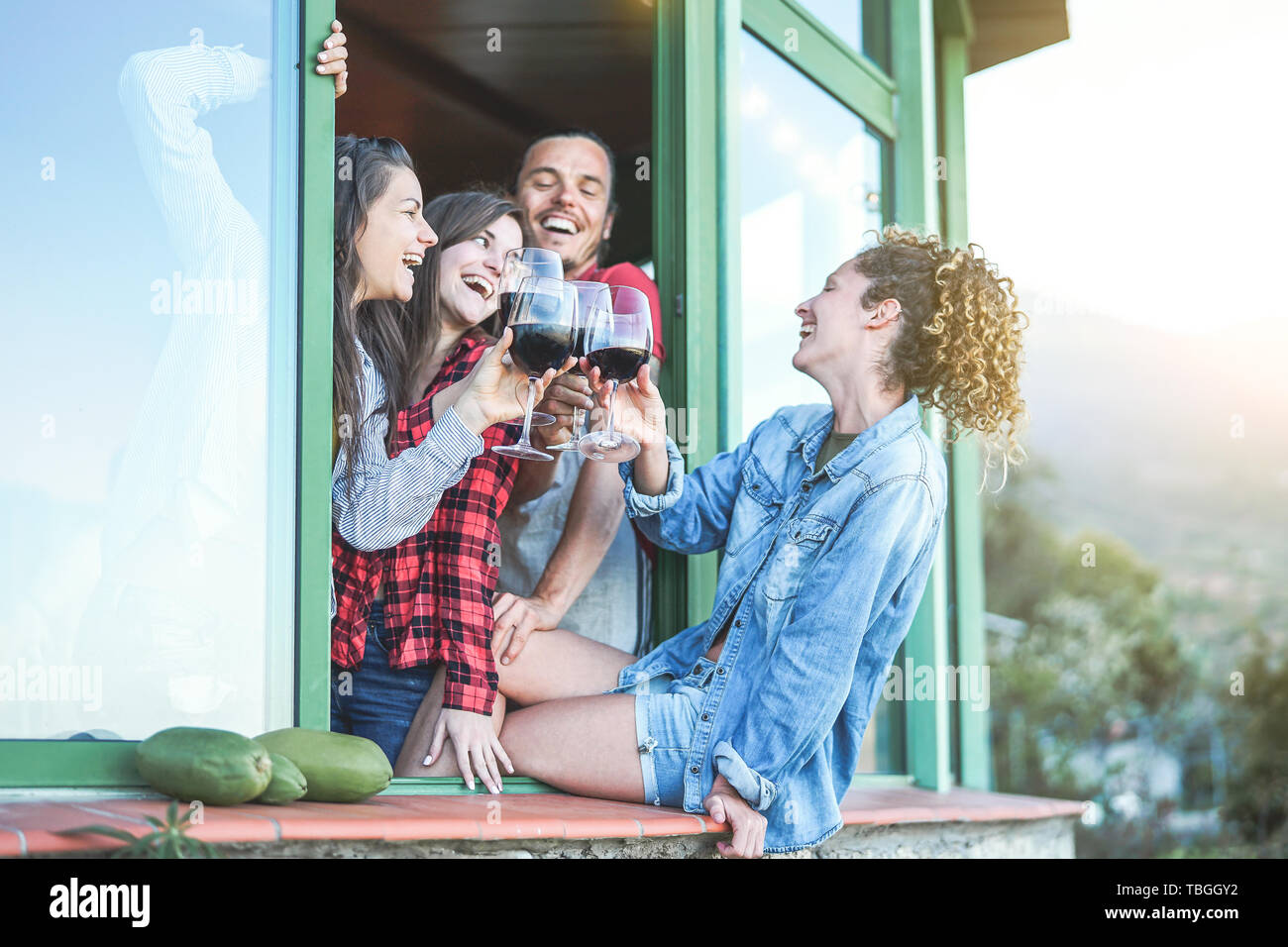 Junge Freunde Toasten mit rotem Wein Partei bei Sonnenuntergang auf Penthouse Terrasse - glückliche Menschen, die Spaß an einem Wochenende sonnigen Tag auf der Terrasse Stockfoto