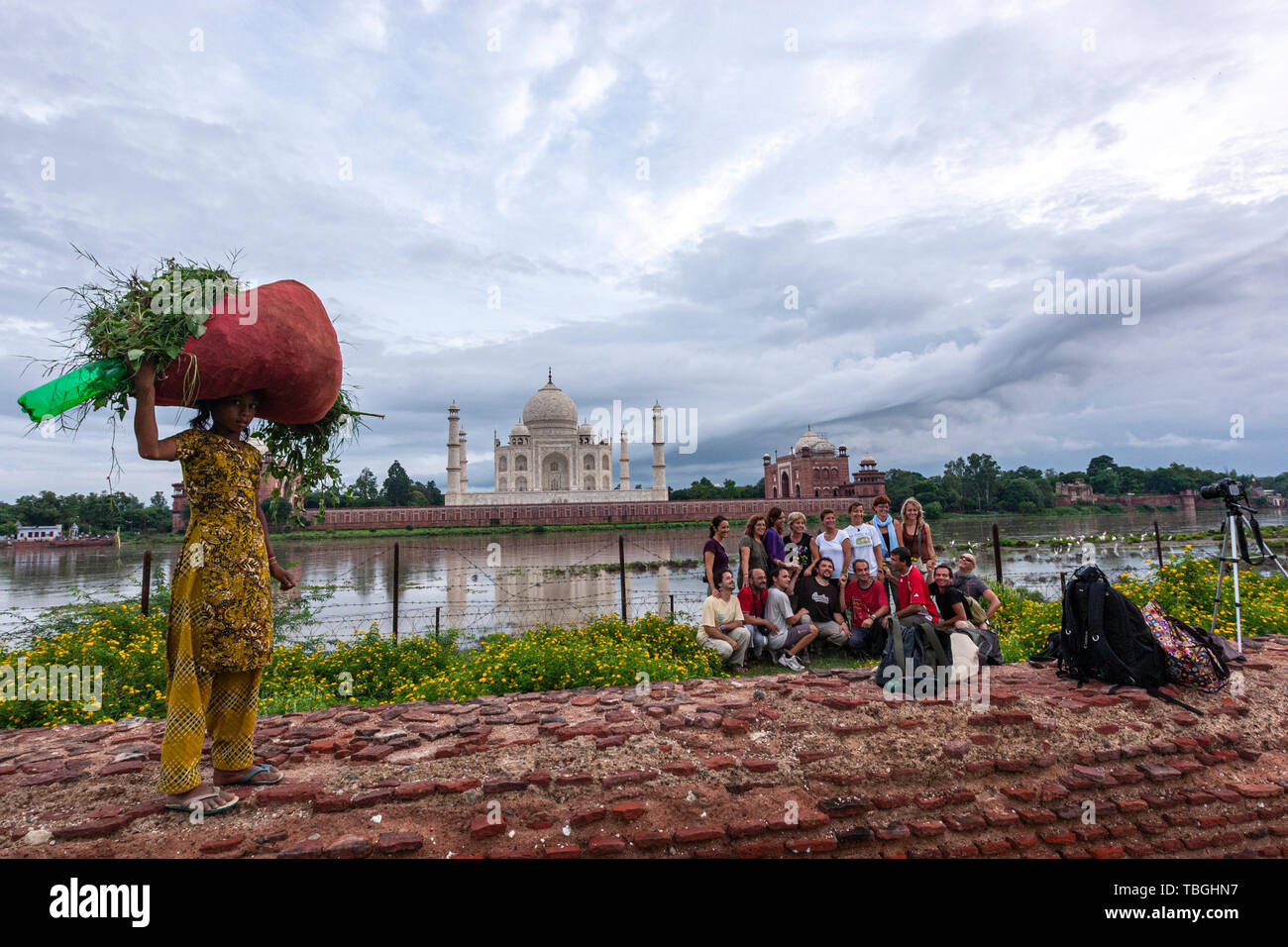 Junge indische Mädchen mit einem roten Sack mit geschnittenen Kräutern und Touristen eine selfie aus in Mehtab Bagh, Taj Mahal View Point, Agra, Uttar Pradesh, Indien Stockfoto