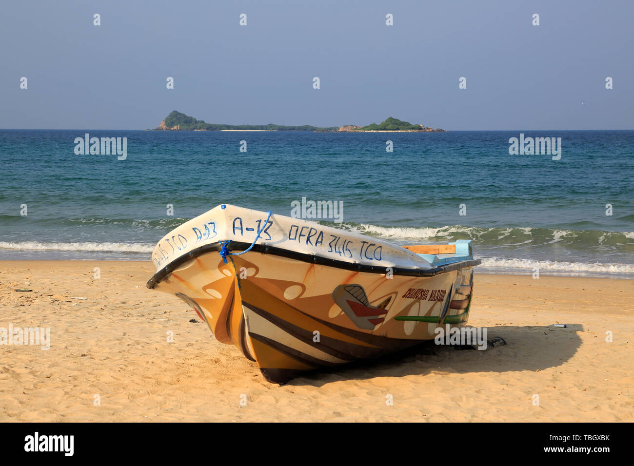 Boot am tropischen Strand bei Nilavelli, Trincomalee, Sri Lanka, Asien mit Pigeon Island im Hintergrund Stockfoto