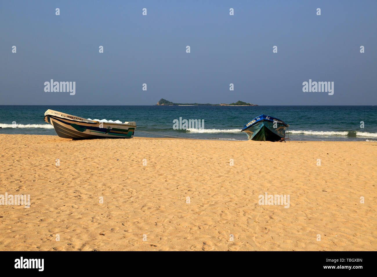 Boote am tropischen Strand bei Nilavelli, Trincomalee, Sri Lanka, Asien mit Pigeon Island im Hintergrund Stockfoto