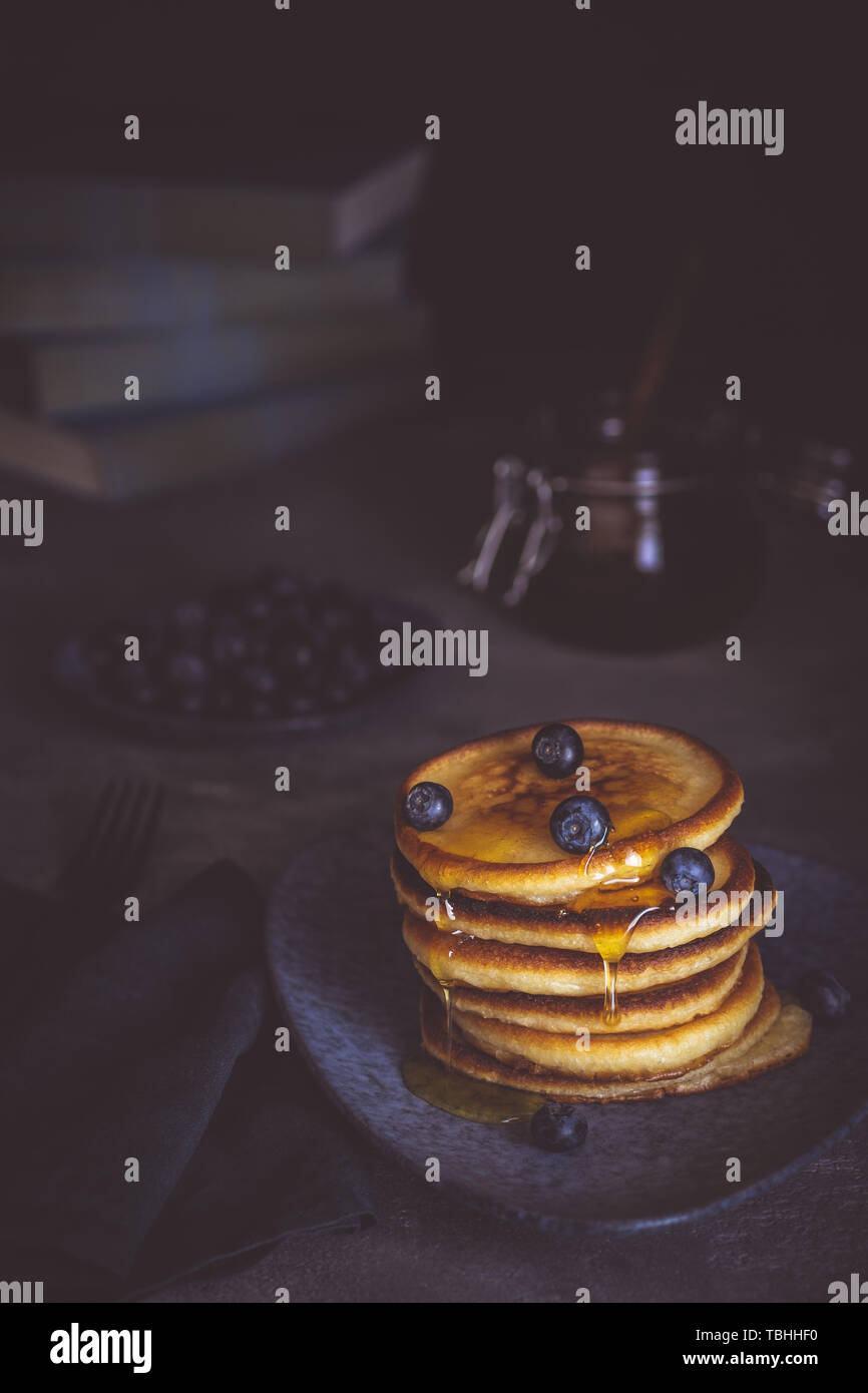 Pfannkuchen mit frischen Beeren und Ahornsirup auf dunklem Hintergrund. Klassische amerikanische hausgemachtes Frühstück. Stockfoto