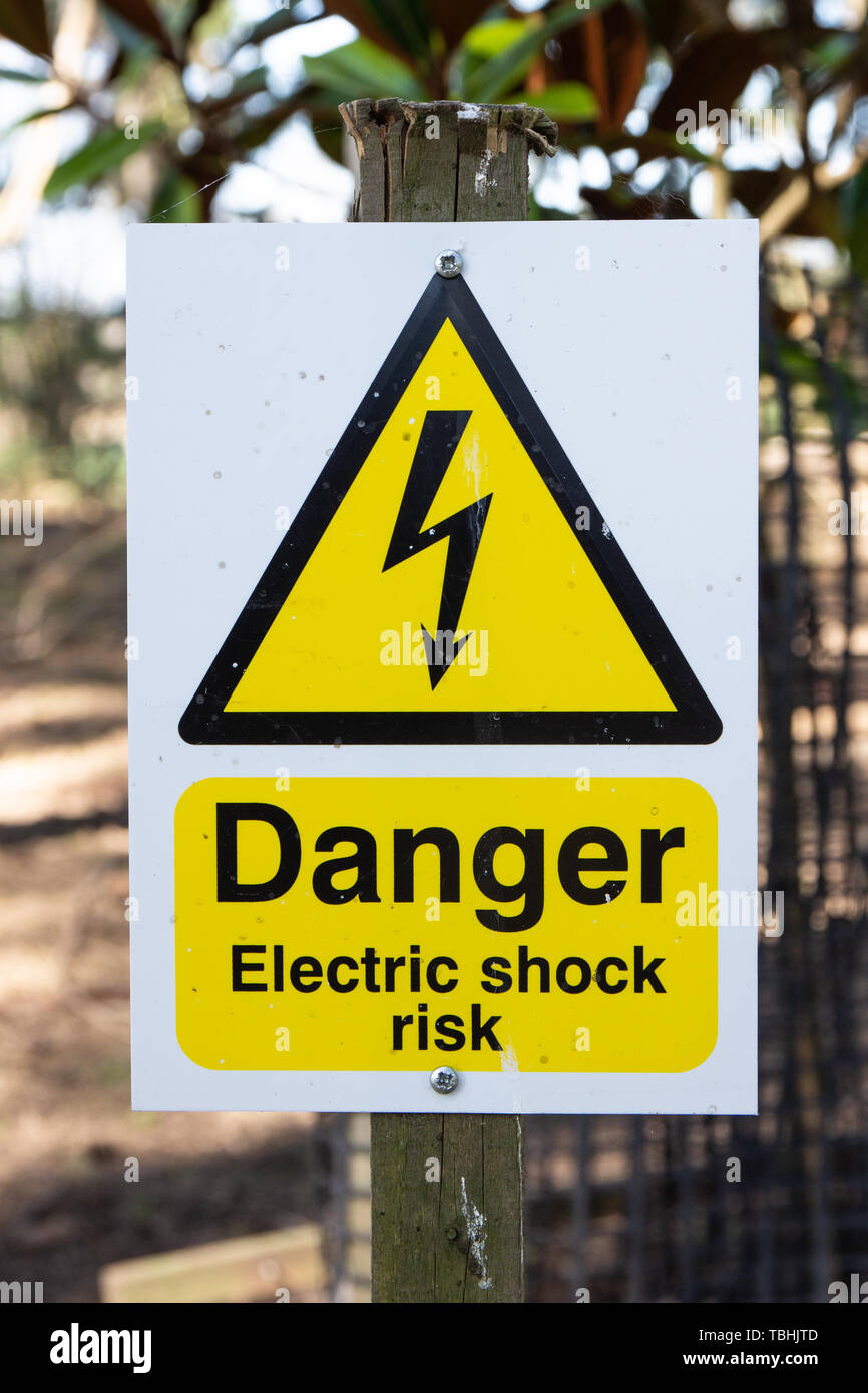 Weiß elektrischer Zaun Warnblinkanlage Schild mit Text Gefahr von elektrischen Schlägen auf einem Bauernhof außerhalb Stockfoto Weiß elektrischer Zaun Warnblinkanlage Schild mit Text Gefahr von elektrischen Schlägen auf einem Bauernhof außerhalb Stockfoto