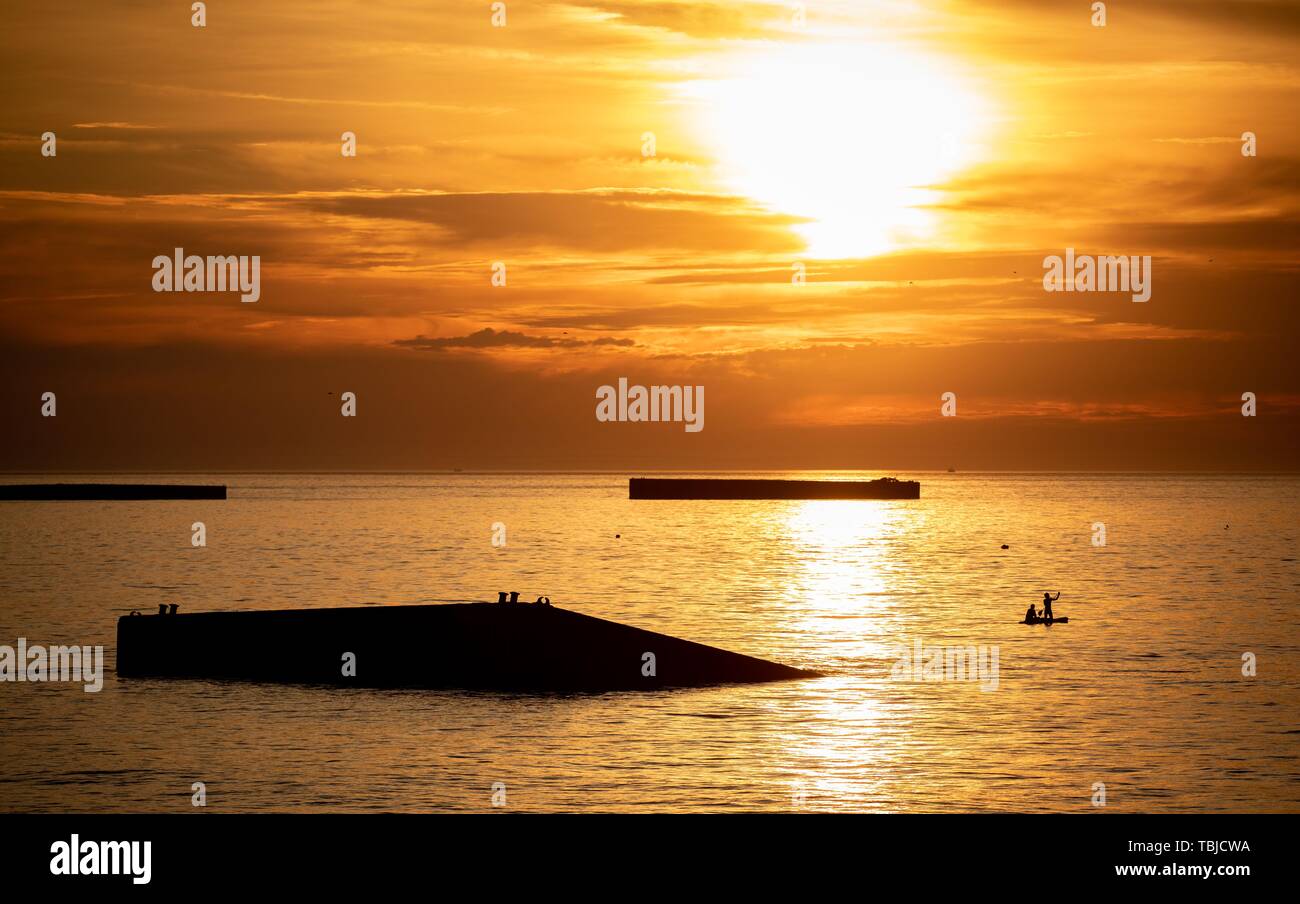 Arromanches-Les-Bains, Frankreich. 02 Juni, 2019. 01. Juni 2019, France (Frankreich), Arromanches-Les-Bains: Überreste des ehemaligen Hafen kann bei Gold Strand während der Ebbe in den Sonnenuntergang gesehen werden. Nach der Landung der alliierten Truppen eine der zwei künstliche Häfen (Mulberry B) gebaut wurde an der Küste von Arromanches-les-Bains, durch die Truppen und liefert an Land gebracht wurden. 06.06.2019 ist der 75. Jahrestag der Landung der alliierten Truppen in der Normandie (D-Day). Quelle: dpa Picture alliance/Alamy leben Nachrichten Stockfoto