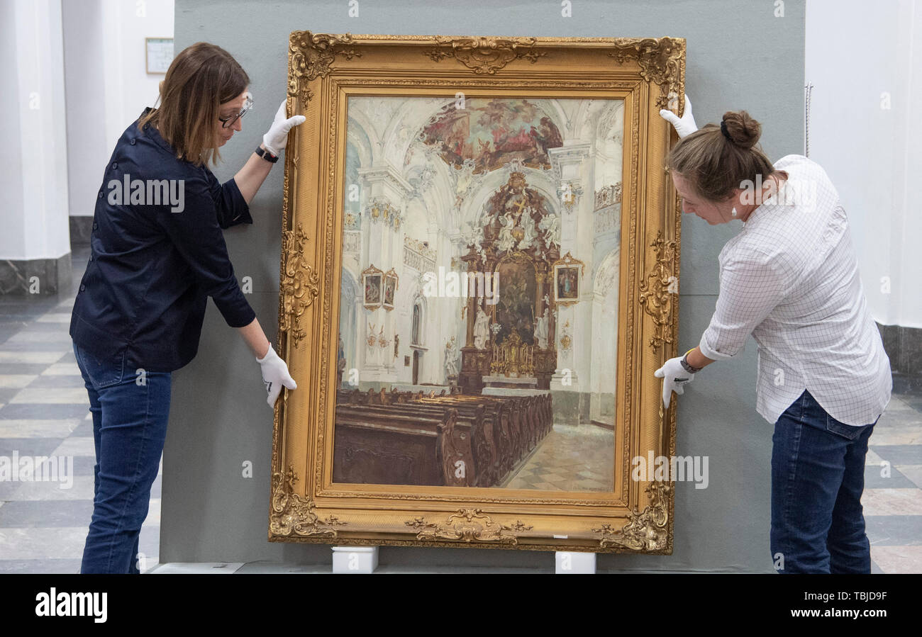 Wiesbaden, Deutschland. 21 Mai, 2019. Zwei Mitarbeiter des Landesmuseums drücken Sie die Malerei" Kirche zu Rott am Inn" von Fritz Beckert auf einem Wagen durch den Eingangsbereich. Einige der Kunstwerke, die die Nationalsozialisten von ihren Besitzern gestohlen hatte, sind noch in den Sammlungen der Hessischen Museen heute gespeichert. (Zu dpa' Herkunft Forschung: Wissenschaft trifft Kunst" vom 02.06.2019) Credit: Boris Roessler/dpa/Alamy leben Nachrichten Stockfoto