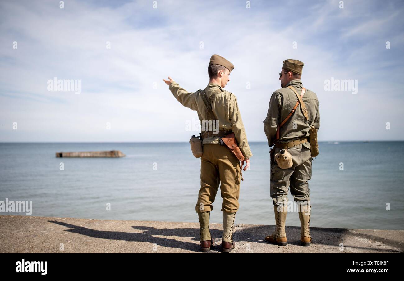 Arromanches-Les-Bains, Frankreich. 02 Juni, 2019. Arromanches-Les-Bains: Zwei Männer in historischen Uniformen der US-Soldaten unterhalten vor der Reste des ehemaligen Hafen von Gold Beach. Nach der Landung der alliierten Truppen im Zweiten Weltkrieg, einer der zwei künstliche Häfen (Mulberry B) gebaut wurde an der Küste von Arromanches-les-Bains, durch die Truppen und liefert an Land gebracht wurden. 06.06.2019 ist der 75. Jahrestag der Landung der alliierten Truppen in der Normandie (D-Day). Quelle: dpa Picture alliance/Alamy leben Nachrichten Stockfoto