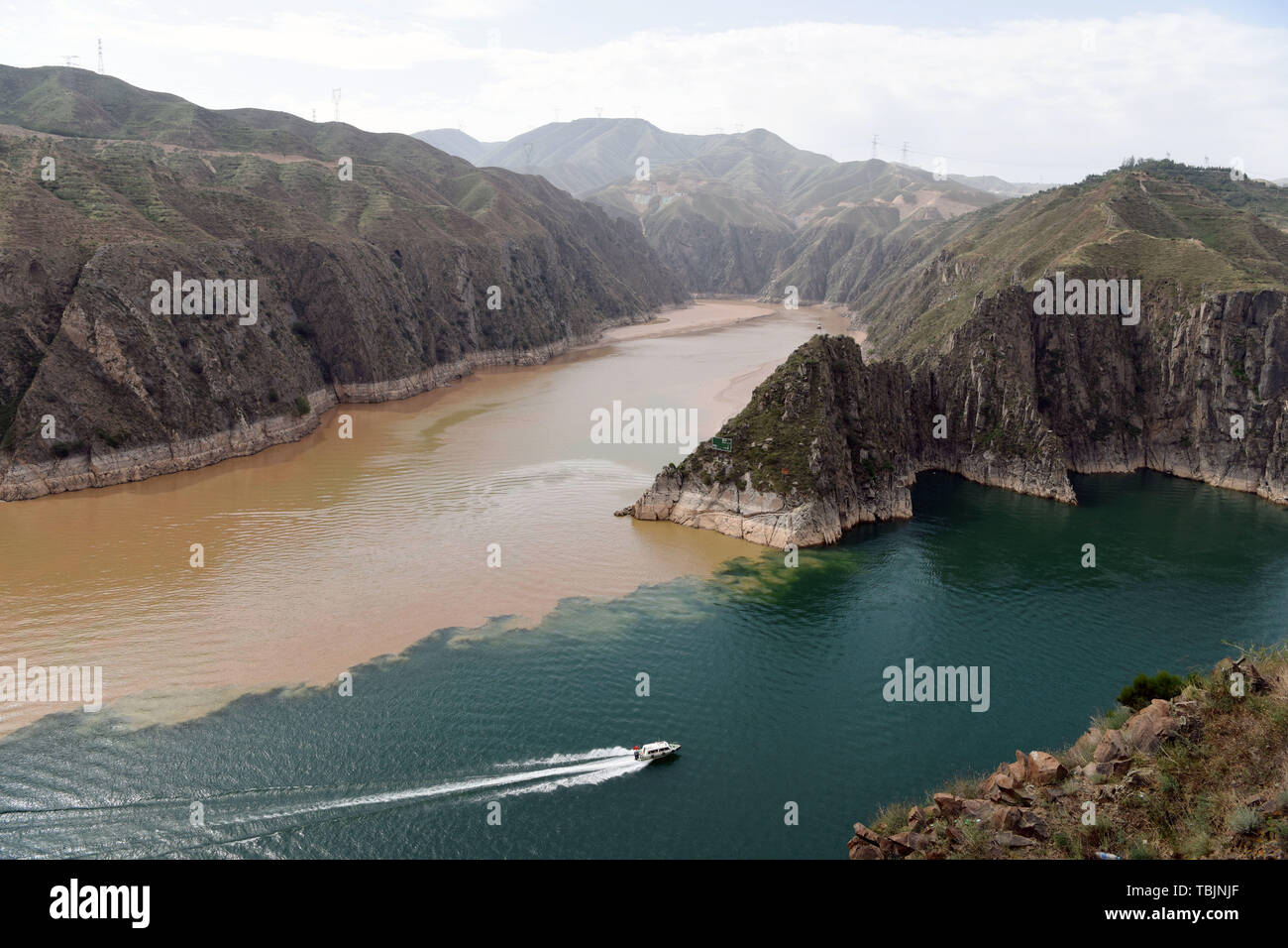 Yongjing. 2. Juni 2019. Foto am 2. Juni 2019 zeigt eine Yacht segeln im Stausee in Liujiaxia Yongjing County im Nordwesten der chinesischen Provinz Gansu. Ein scharfer Kontrast der Farben ist klar gezeigt, wenn zwei Flüsse, Schlamm-Gelben Fluss und seinen Beiträgen Taohe Fluss, fließt mit einer großen Menge von Schlamm und Sand in der Liujiaxia Behälter, die weit verbreitet ist - für sein klares Wasser bekannt. Quelle: Ma Ning/Xinhua/Alamy Leben Nachrichten Quelle: Xinhua/Alamy leben Nachrichten Stockfoto