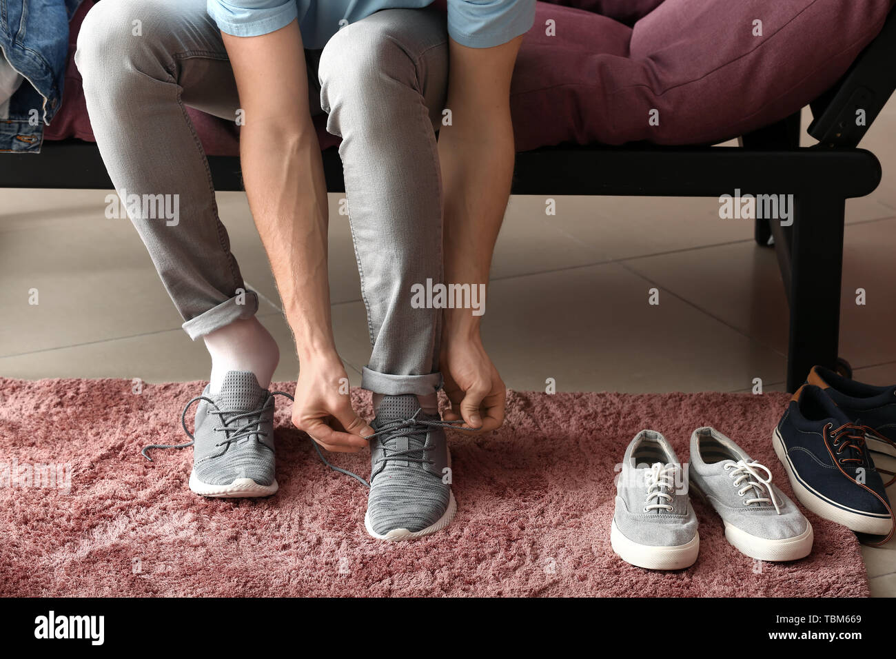 Junger Mann auf Schuhe im Zimmer Stockfoto