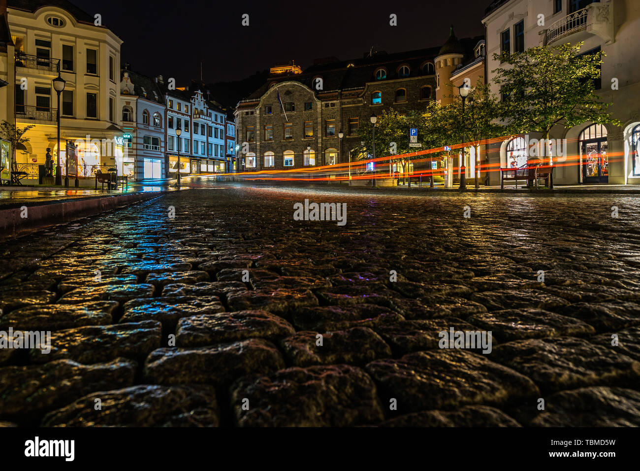 Nacht Blick auf einen typischen gepflasterten Straße in Alesund Stadtzentrum mit einem Auto licht Trail. Alesund, Mehr og Romsdal, Norwegen, August 2018 Stockfoto