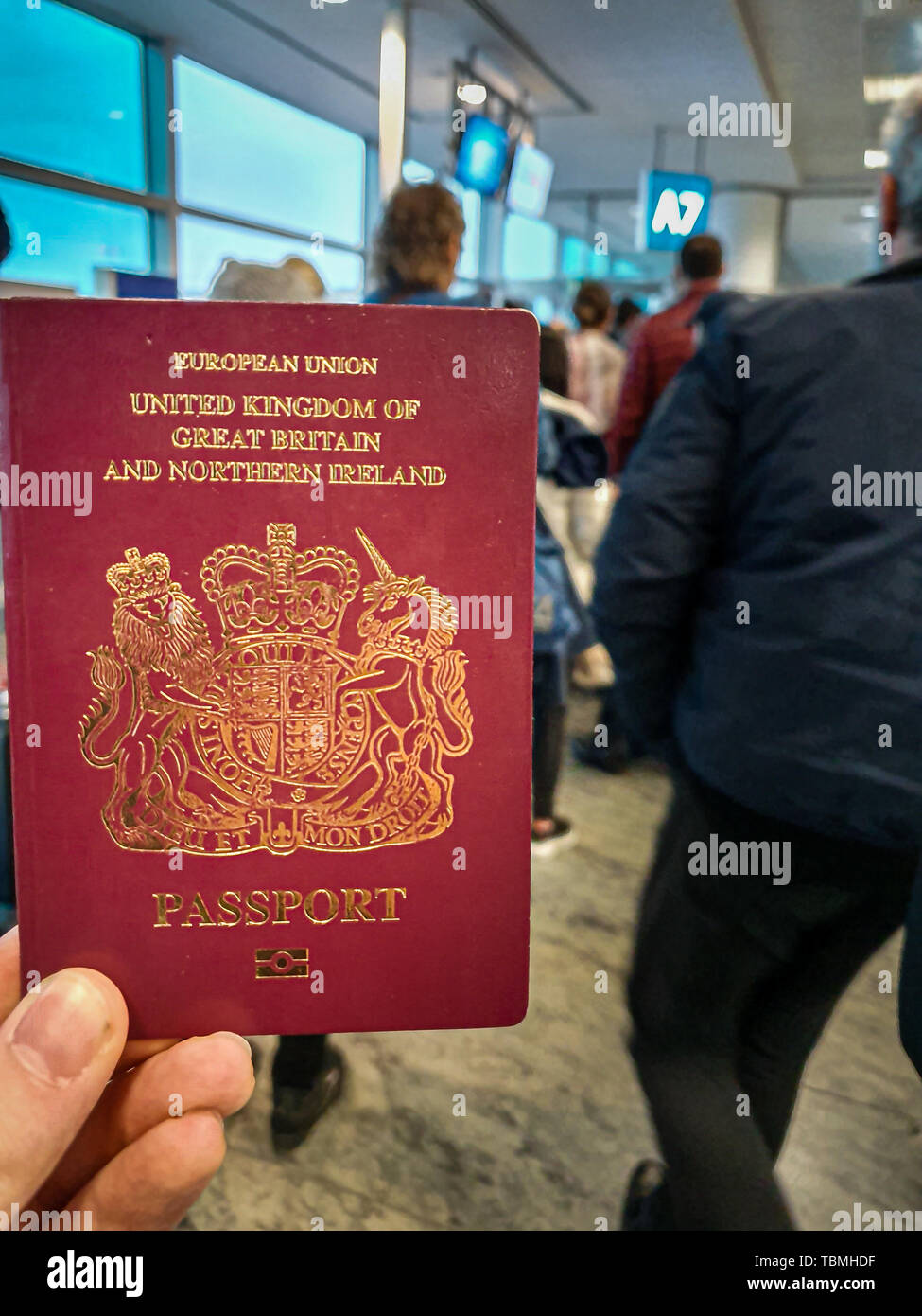 Einen weißen Mann hält seine roten britischen Paß in der Hand in der Mitte von einem überfüllten Abflugterminal Stockfoto