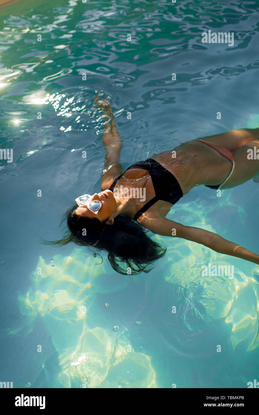 Brunette kaukasische Frau im Bikini schwimmend im Wasser im Pool Stockfoto