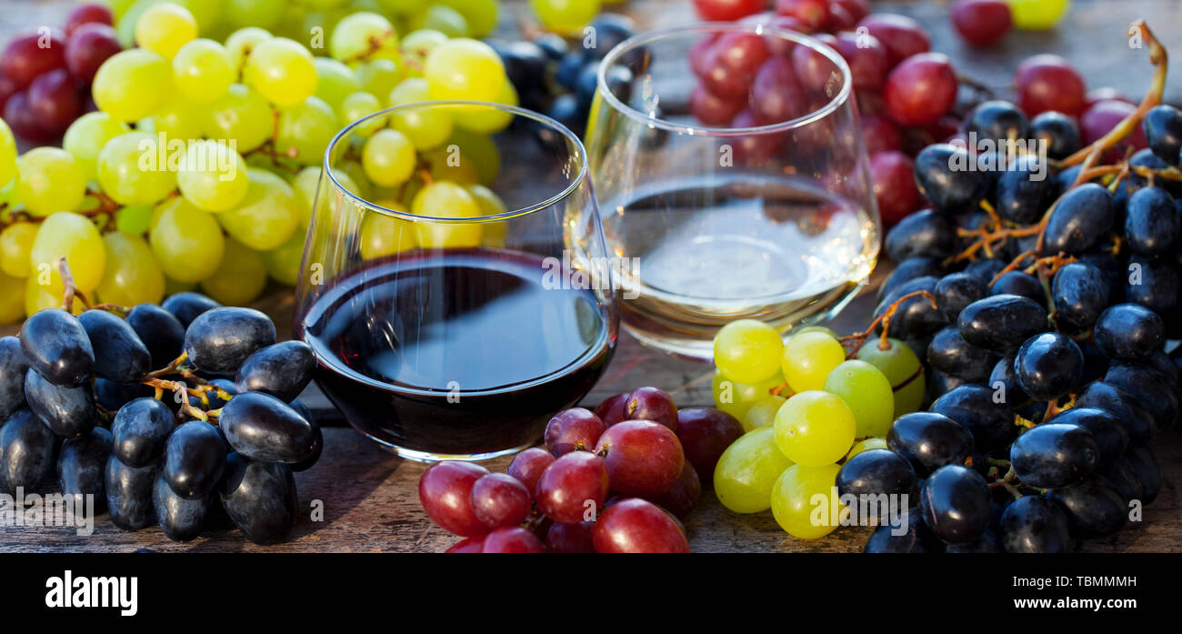 Glas Rot- und Weißwein mit frischen Weintrauben Sortiment auf Holztisch. Nahaufnahme Stockfoto