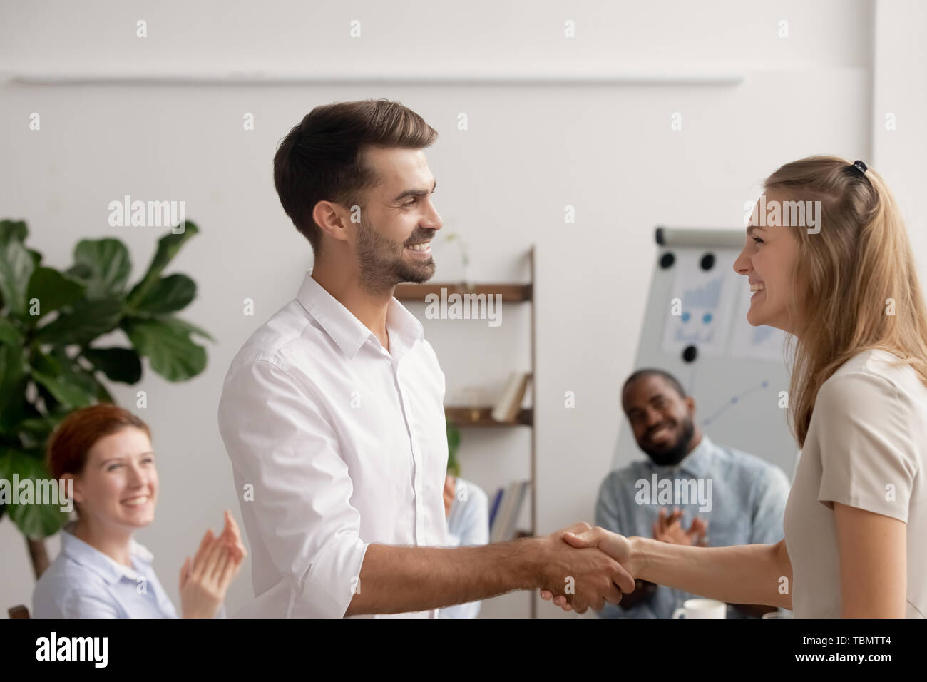 Junge Mitarbeiter ermutigend für gute Projektergebnisse Handshake mit dem Regisseur Stockfoto