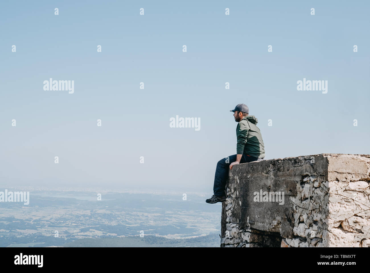 Mann mit Kappe sitzt Rückseite Blick von oben von Gebäude Stockfoto Mann mit Kappe sitzt Rückseite Blick von oben von Gebäude Stockfoto