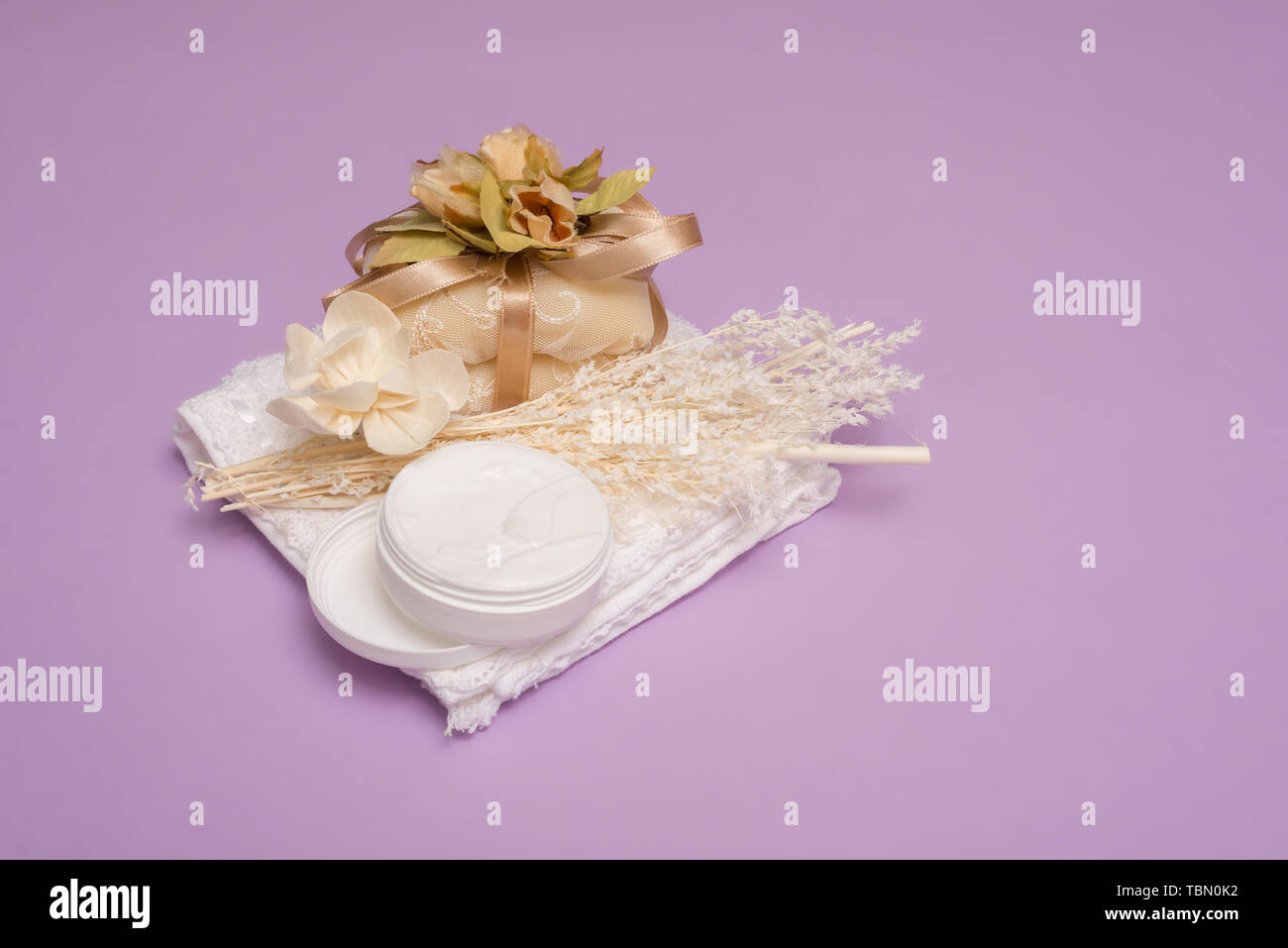 Schönheit mit Körper Creme Seife, Kerze und weißen Tischdecke auf einem violetten Hintergrund Stockfoto