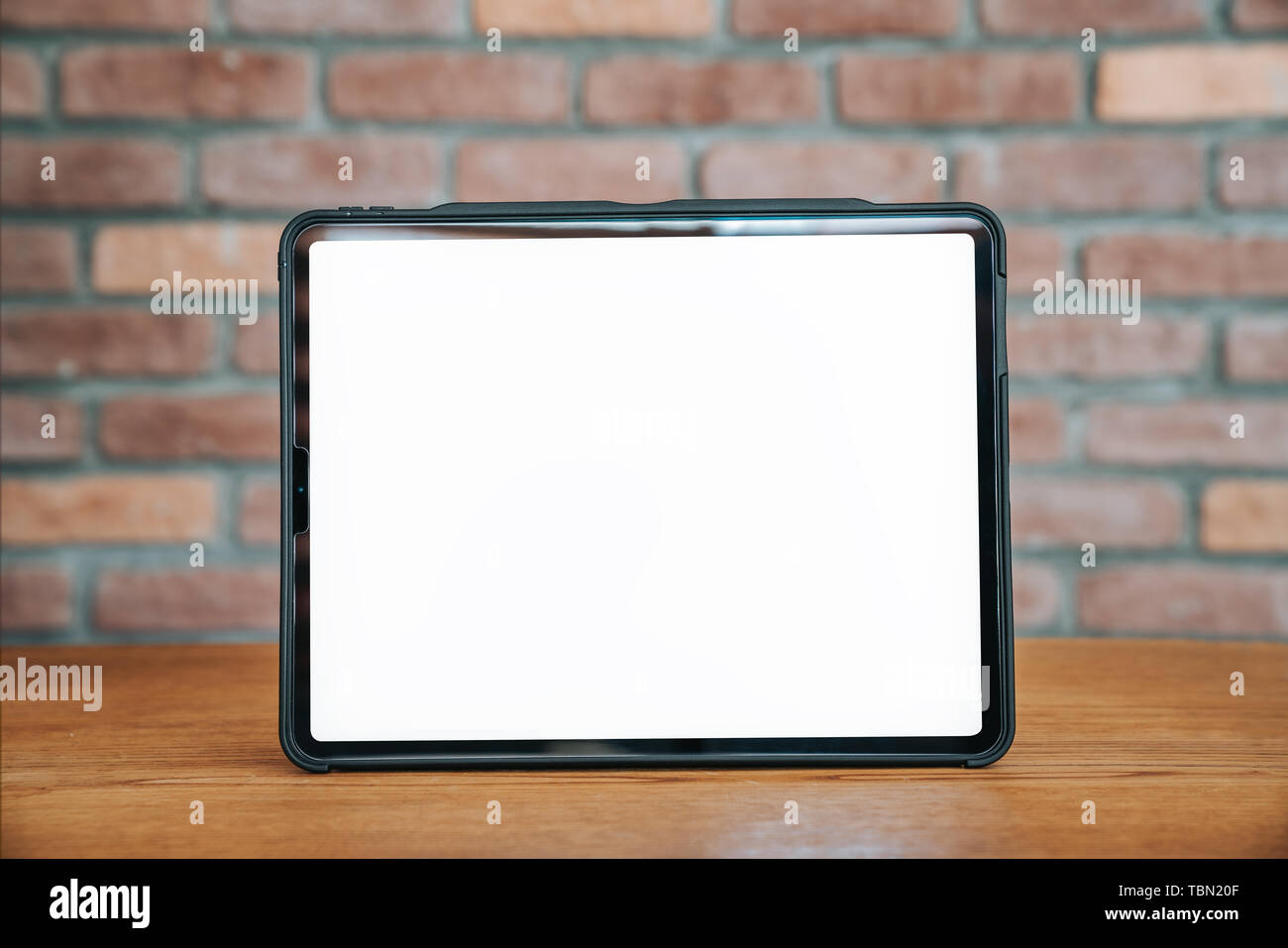 Schwarze Tablette mit leeren Bildschirm auf dem Holztisch. Technologie Werbung Konzept. Stockfoto