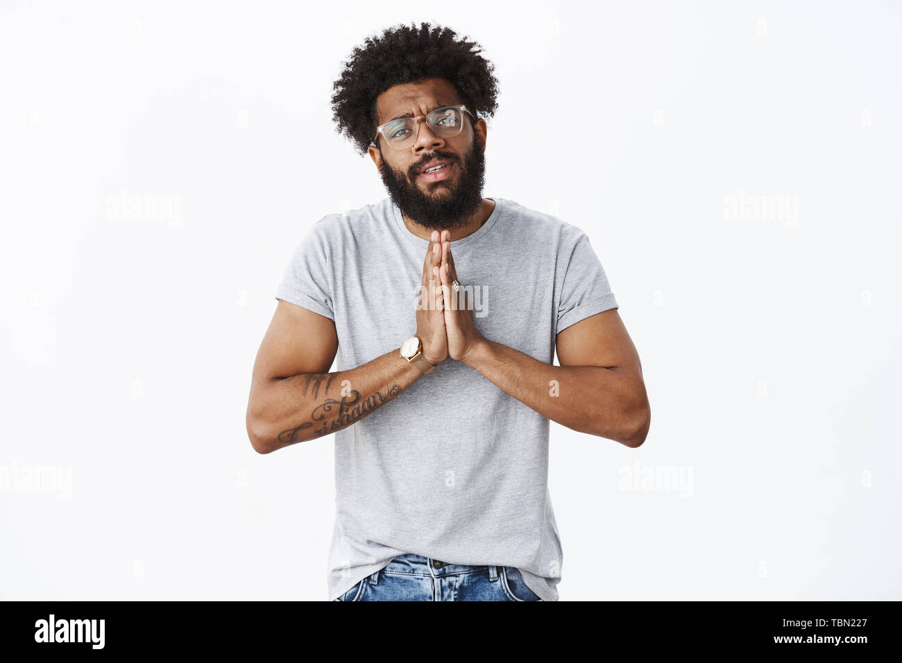 Unbehaglich afrikanische amerikanische Mann in Not mit Brille und Uhr Hände halten in beten Grimassen, um Hilfe und Gnade um Gnade winseln intensiv und si Stockfoto
