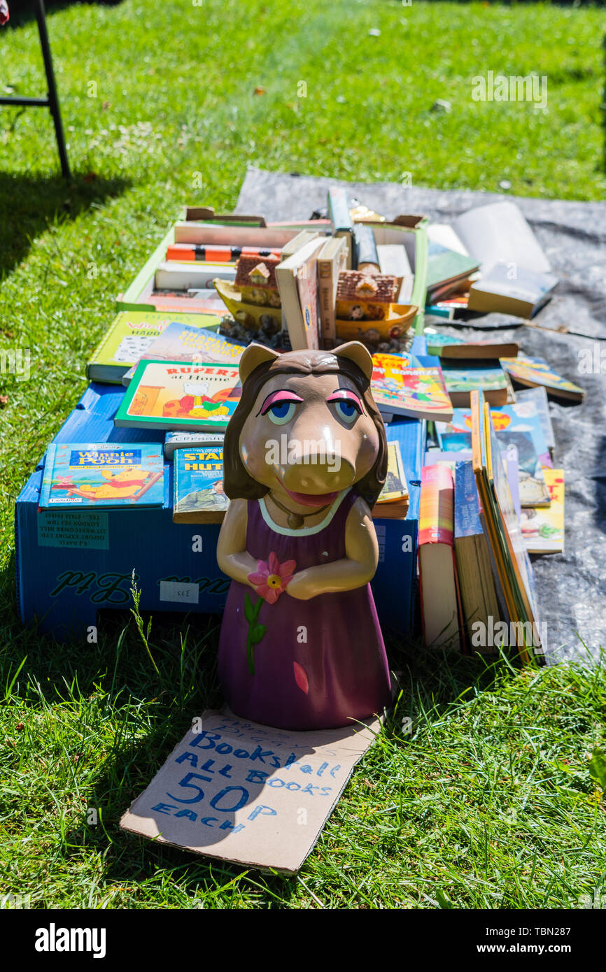 Eine keramische Miss Piggy Figur vor einer Auswahl von Second Hand Bücher der Kinder auf ein Stück Plastik zu einem carboot Verkauf Stockfoto