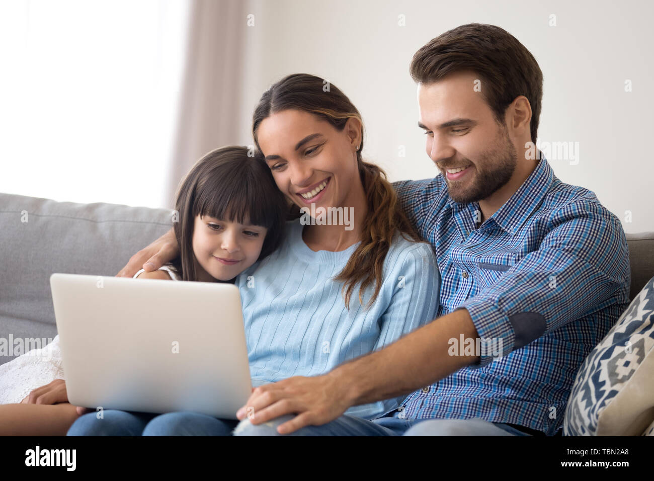 Glückliche junge Eltern mit kleinen Tochter watch Cartoon auf Laptop Stockfoto