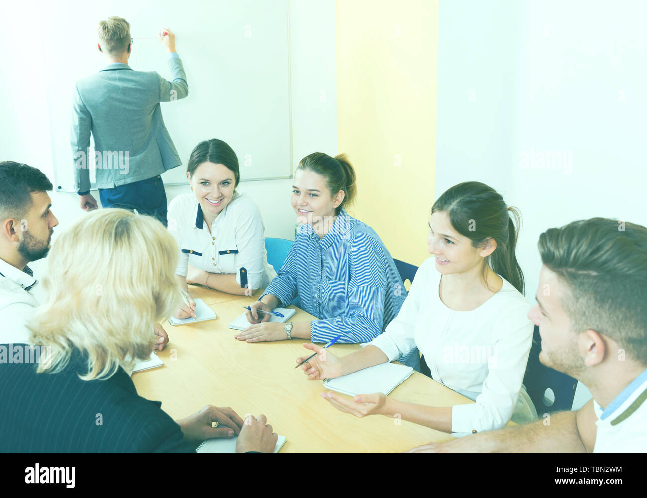 Gruppe der lächelnde Schüler im Klassenzimmer Brainstorming während man Schüler Schreiben auf dem Whiteboard Stockfoto