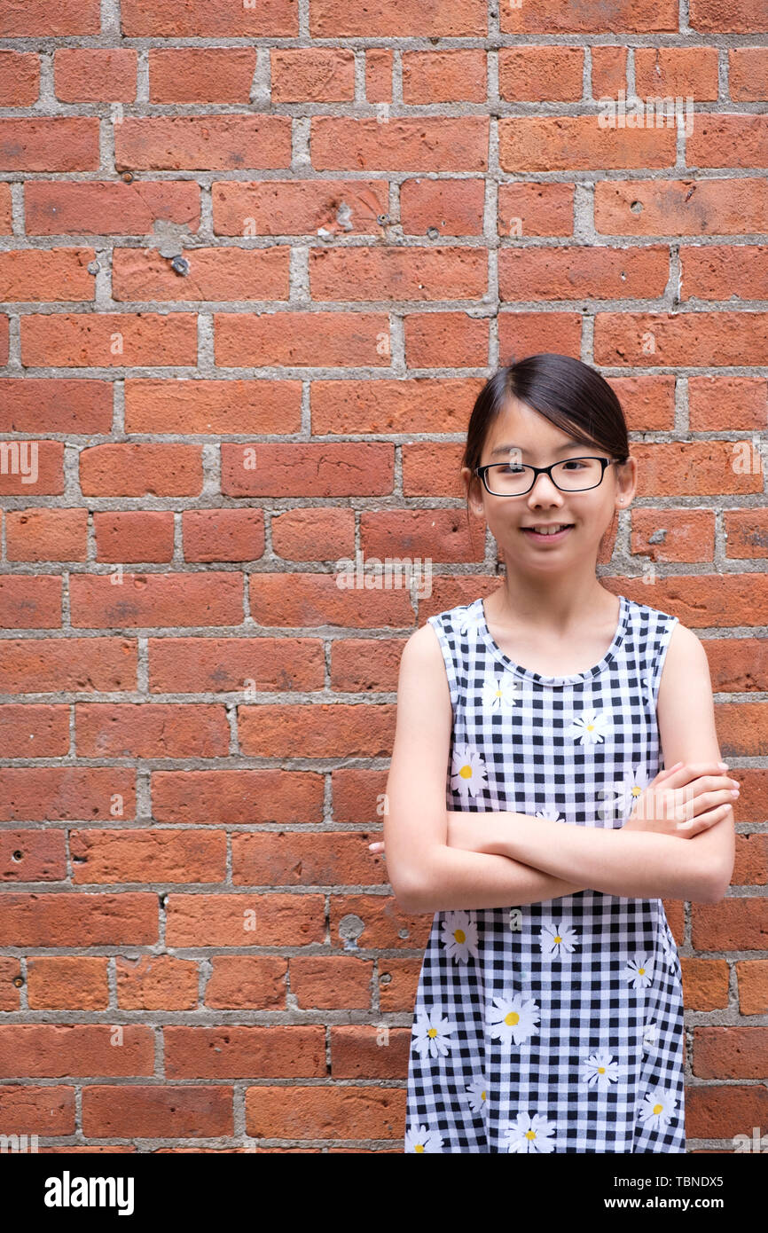 Portrait von jungen asiatischen Mädchen gegen Red brick wall Stockfoto