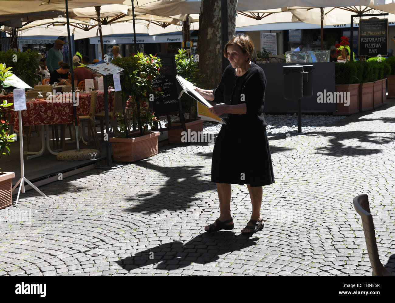 Dame Frau entlang der Straße lesen Zeitung Journal in Stresa, Italien, 2019 Stockfoto