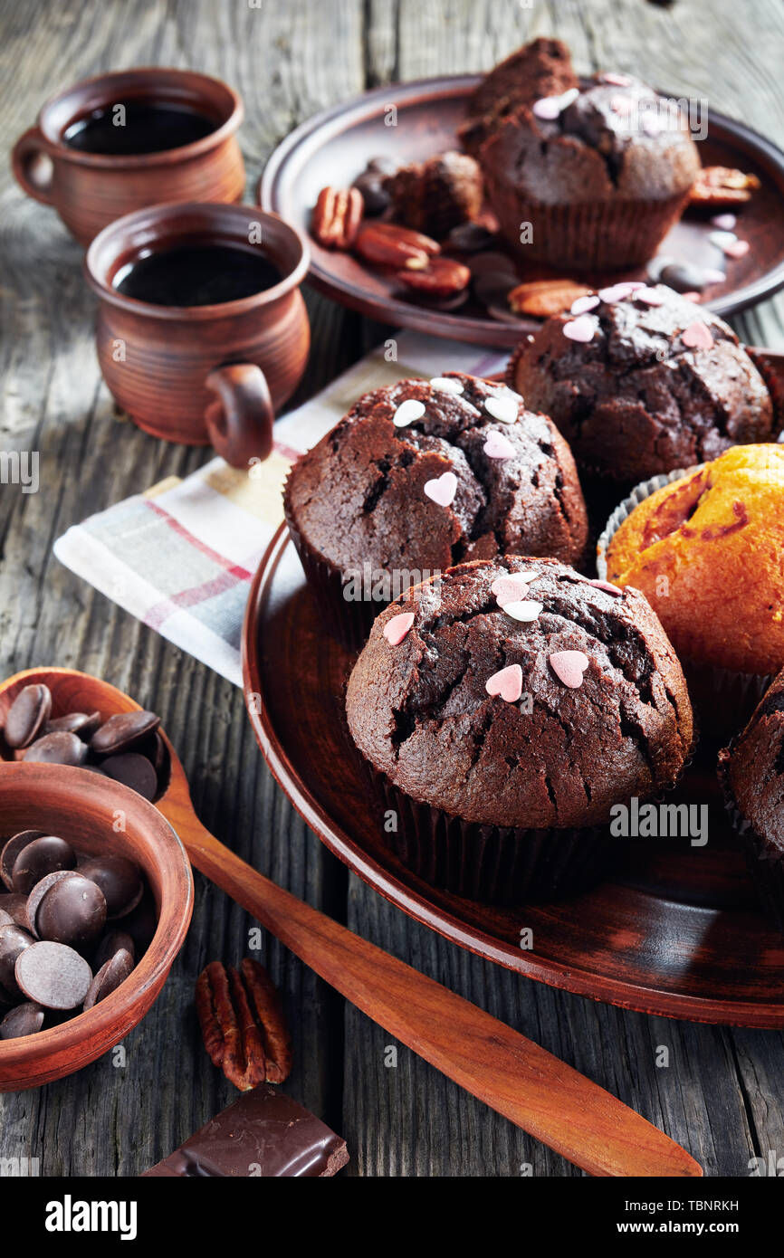 Chocolate pecan Muffins bestreut mit Candy Herz auf Steingut Teller auf einem grauen Holz- Tabelle, Ansicht von oben, close-up Stockfoto