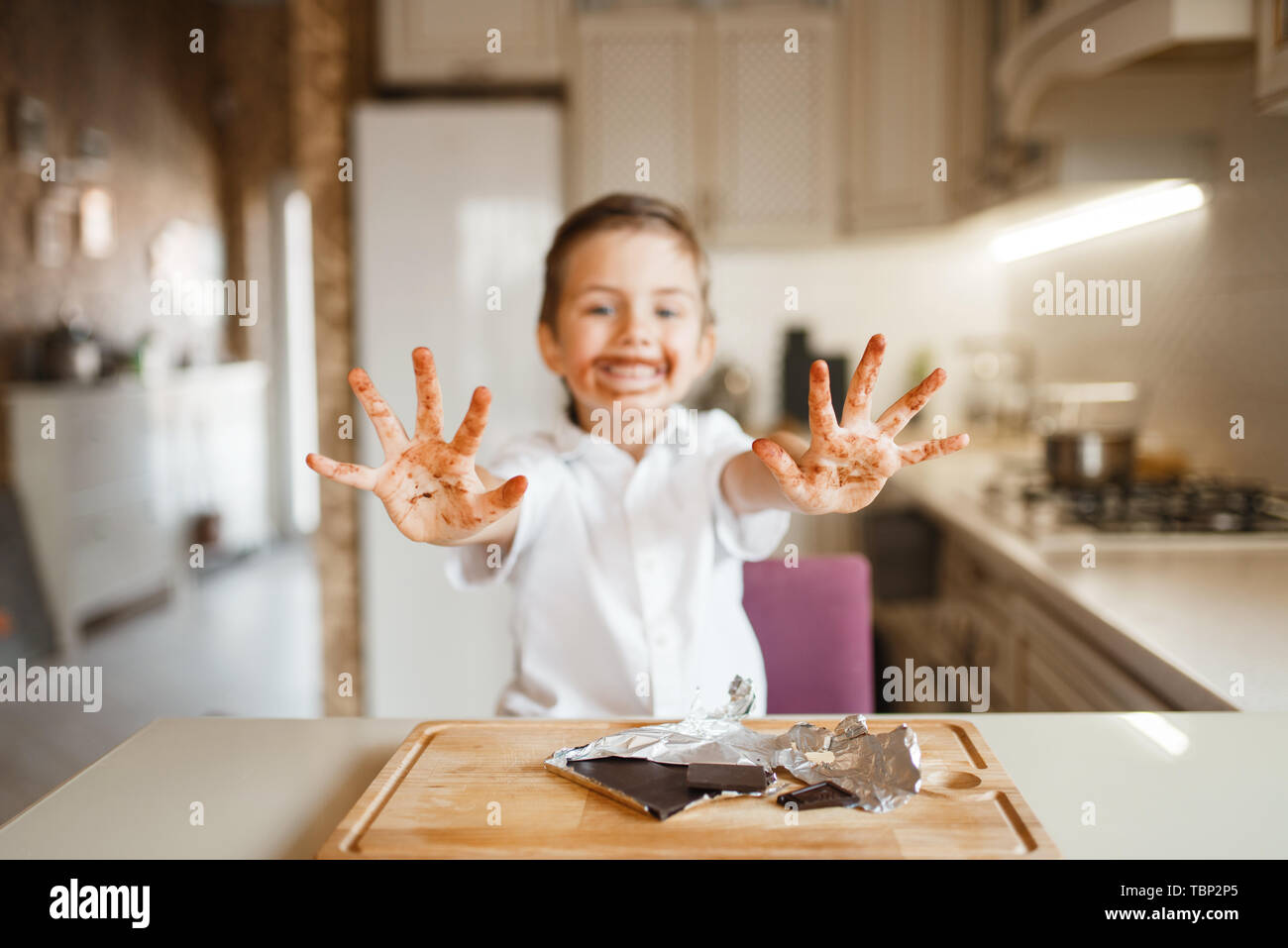 Junge zeigt Hände befleckt mit geschmolzener Schokolade Stockfoto