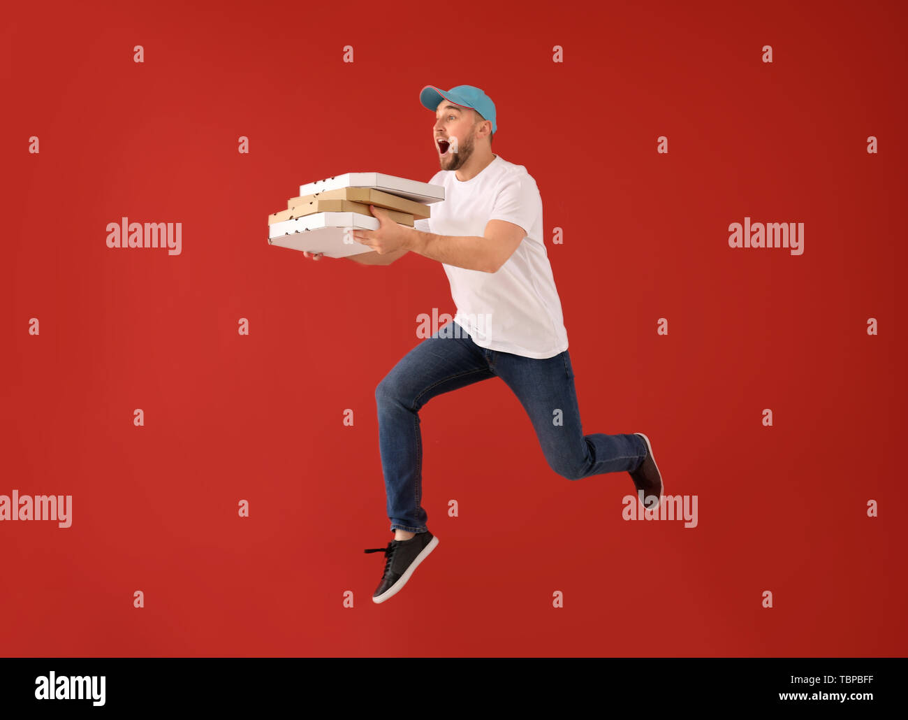 Springen männlichen Kurier mit pizza Schachteln auf farbigen Hintergrund Stockfoto