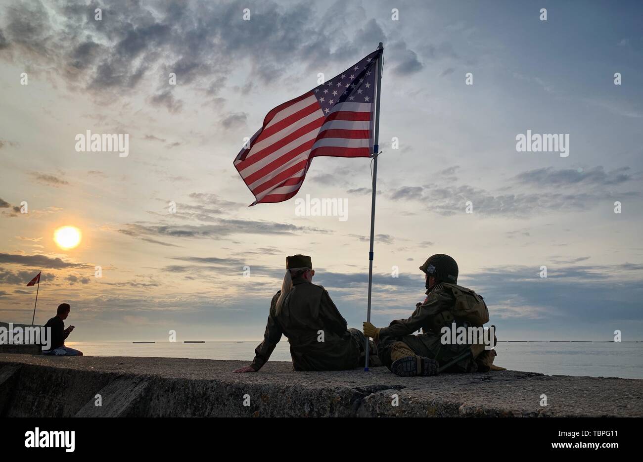 Frankreich. 02. Juni 2019, France (Frankreich), Arromanches-Les-Bains: eine dänische Mutter und Sohn sitzen in historischen Uniformen von US-Soldaten vor der Reste des ehemaligen Hafen am Gold Beach. Nach der Landung der alliierten Truppen eine der zwei künstliche Häfen (Mulberry B) gebaut wurde an der Küste von Arromanches-les-Bains, durch die Truppen und liefert an Land gebracht wurden. 06.06.2019 ist der 75. Jahrestag der Landung der alliierten Truppen in der Normandie (D-Day). Foto: Kay Nietfeld/dpa Stockfoto