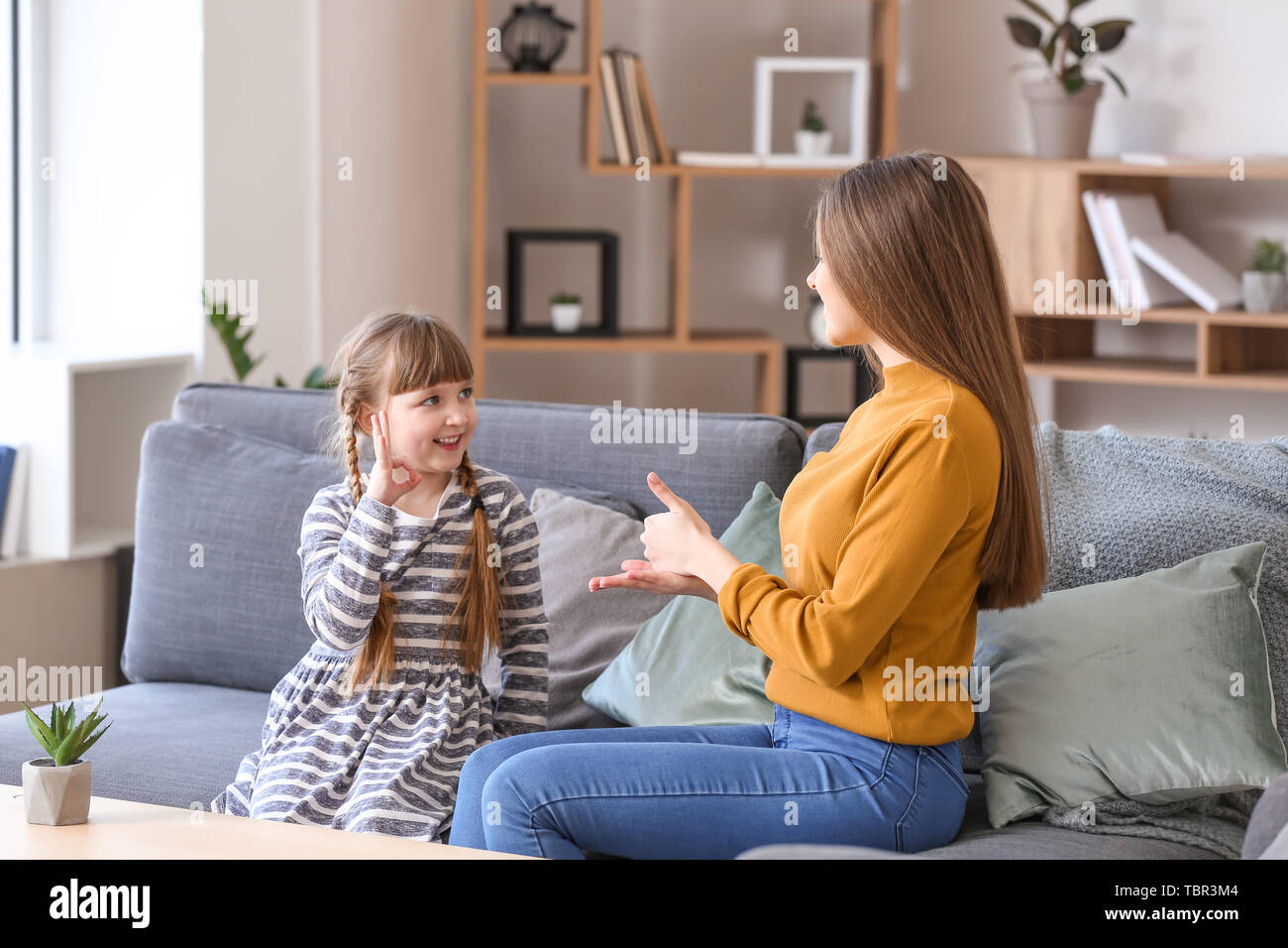 Taubstumme Mutter mit Tochter mit Zeichensprache zu Hause Stockfoto