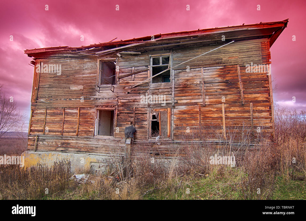 Alte hässliche verfallenes Holzhaus auf einem Hintergrund von roten Himmel bei Sonnenuntergang Stockfoto