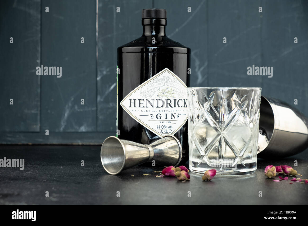 70 cl Flasche Hendricks destillierter Gin mit Glas und Eis auf dunklen rustikalen Hintergrund. Lag neben den Shaker und malenikie rosa Rosen. Stockfoto