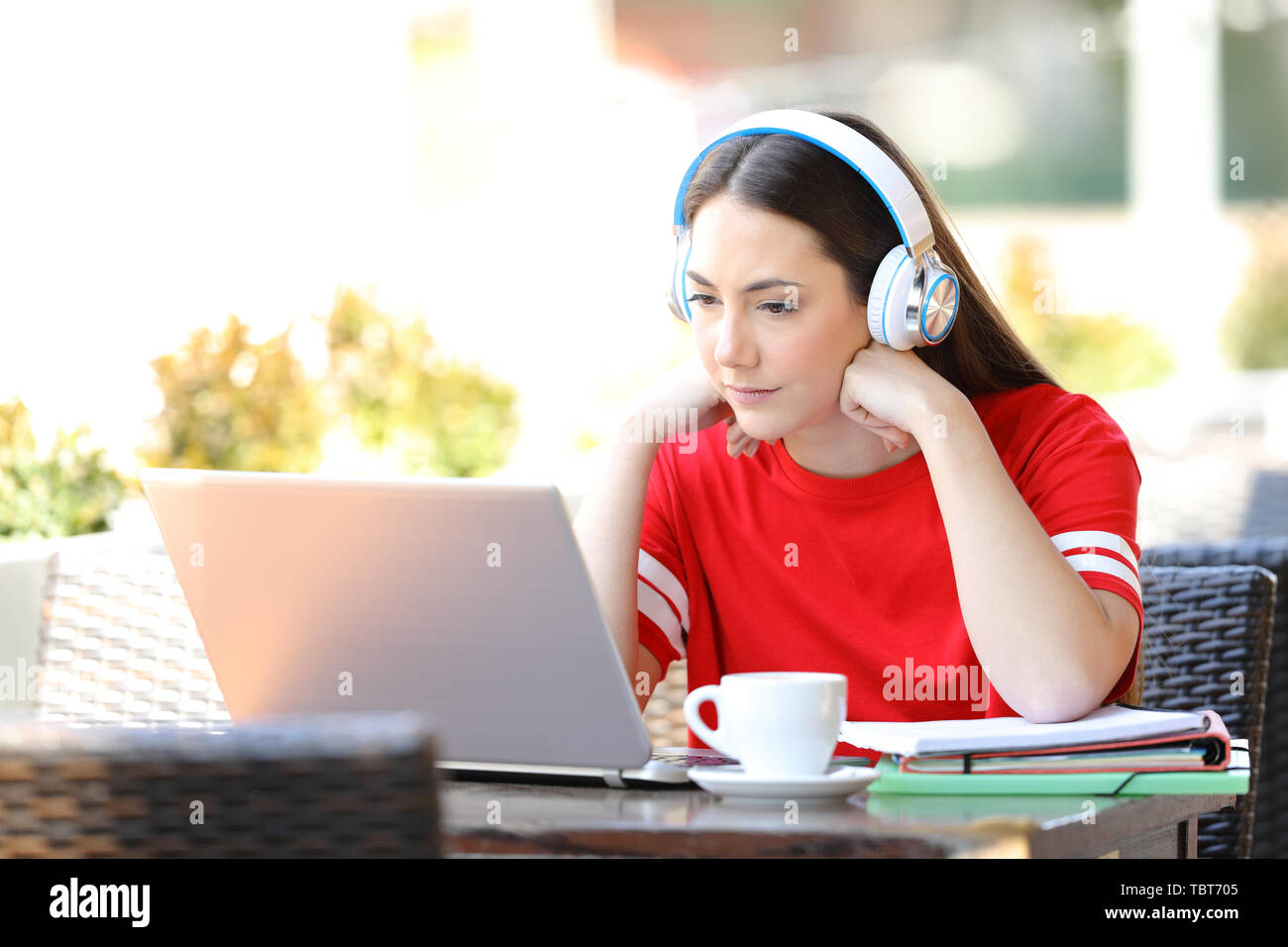 Fleißigen Schüler e-Learning anschauen Tutorials auf Laptop in einem Café Terrasse sitzen Stockfoto