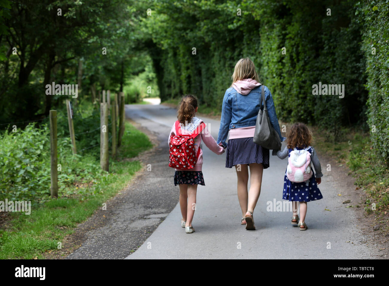 Allgemeine Ansicht der Mutter entlang eine Land weg, während Sie die Hände mit ihren beiden Töchtern 7 und 4 Jahren, West Wittering, West Sussex, UK. Stockfoto