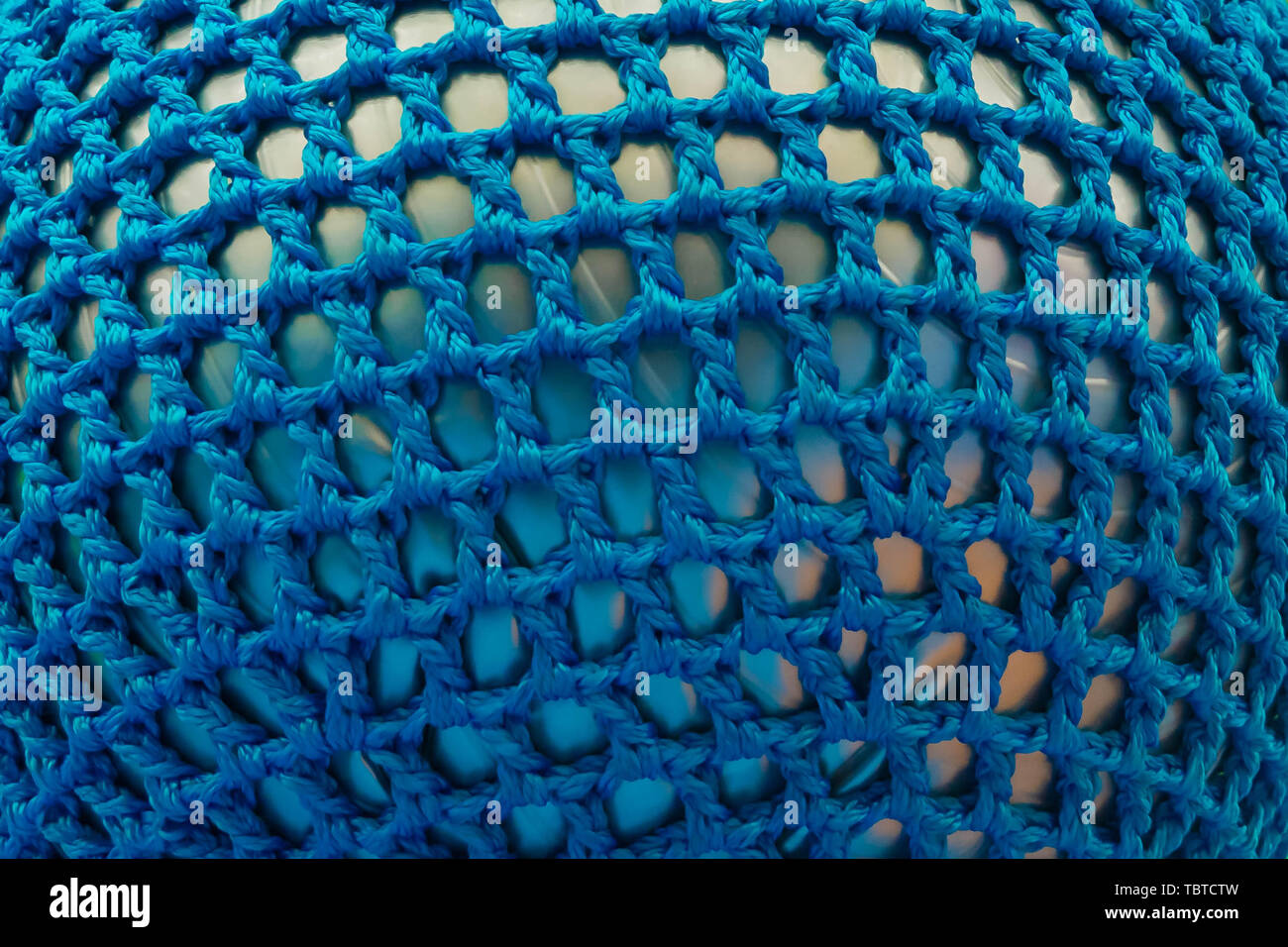 Gummiball, mit blauen Gewebe Gitter abgedeckt. Abstrakte Textur von mehrfarbigen Gewebe. Kreative vintage Hintergrund Stockfoto