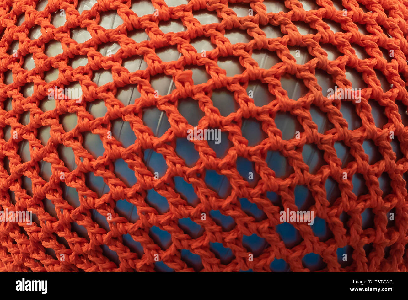 Gummiball, mit einer roten Wicker Gitter abgedeckt. Abstrakte Textur von mehrfarbigen Gewebe. Kreative vintage Hintergrund Stockfoto