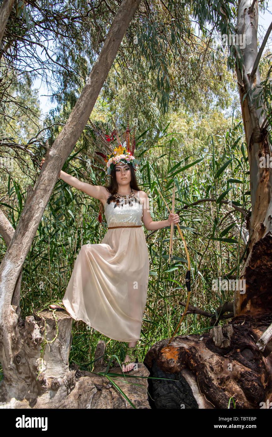 Ein Mädchen im Kleid Pocahontas mit Pfeil und Bogen auf der Eukalyptusbaum Stockfoto