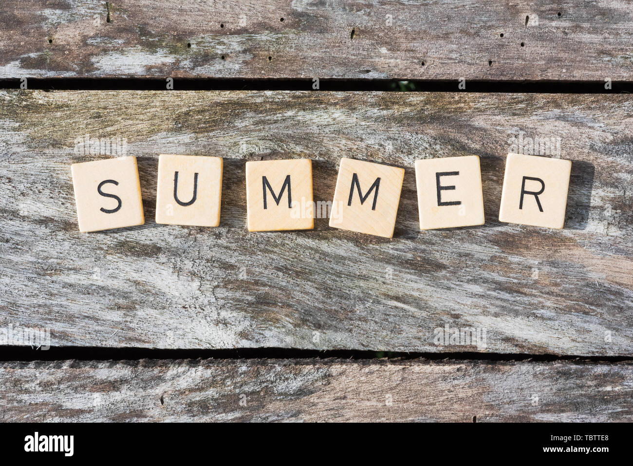 Sommer Buchstaben auf einem Holztisch im Sonnenlicht Top View Stockfoto