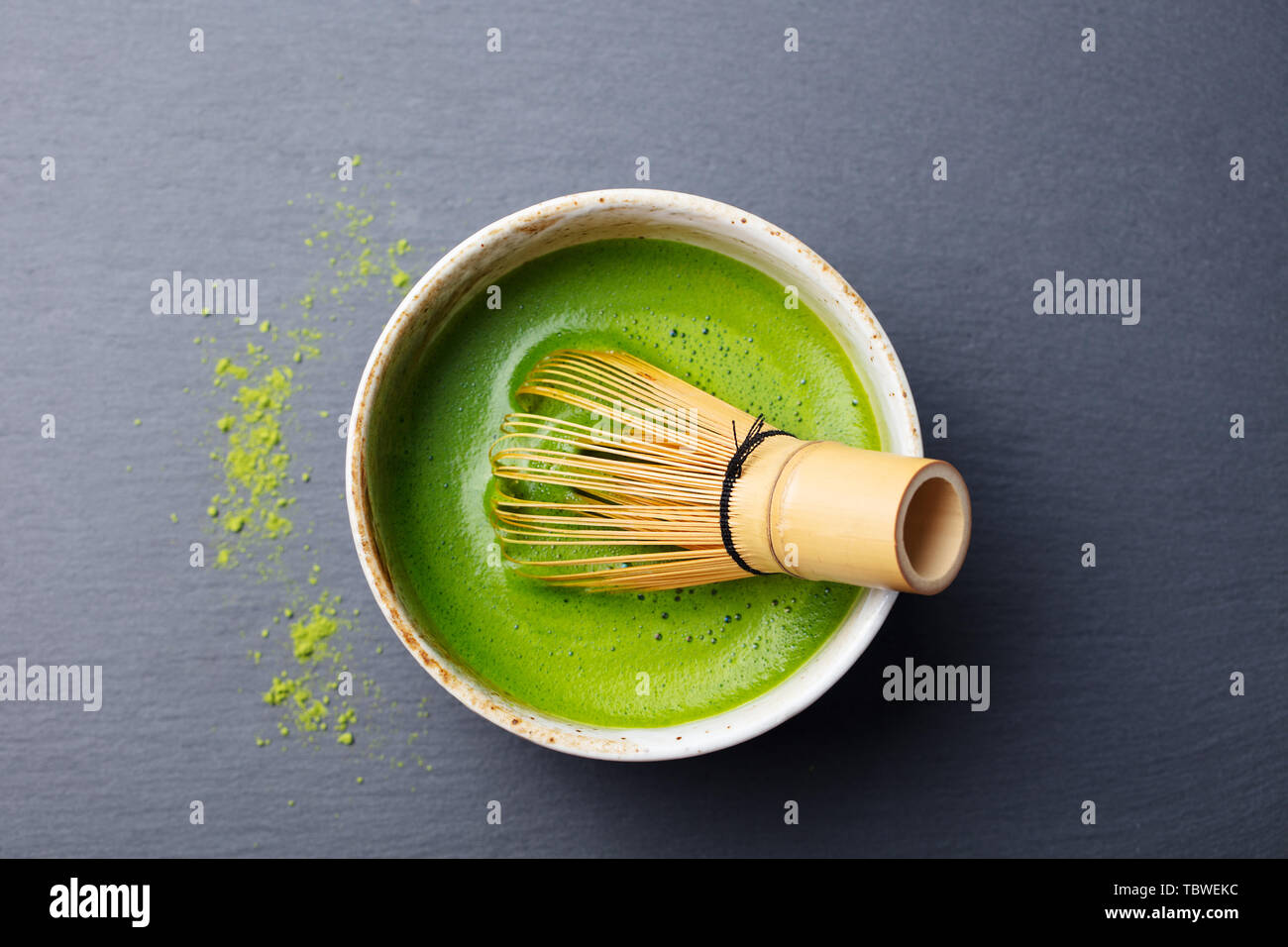 Matcha Grüntee Zubereitung in einer Schüssel mit bambusbesen. Schwarzer Schiefer Hintergrund. Ansicht von oben. Stockfoto