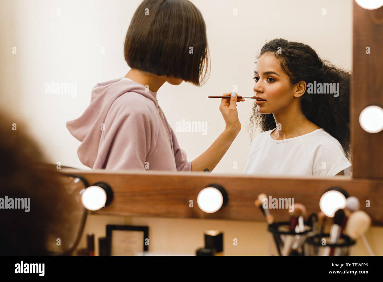 Professional Make up artist Anwendung pomade auf ein Modell vor einem Spiegel Stockfoto