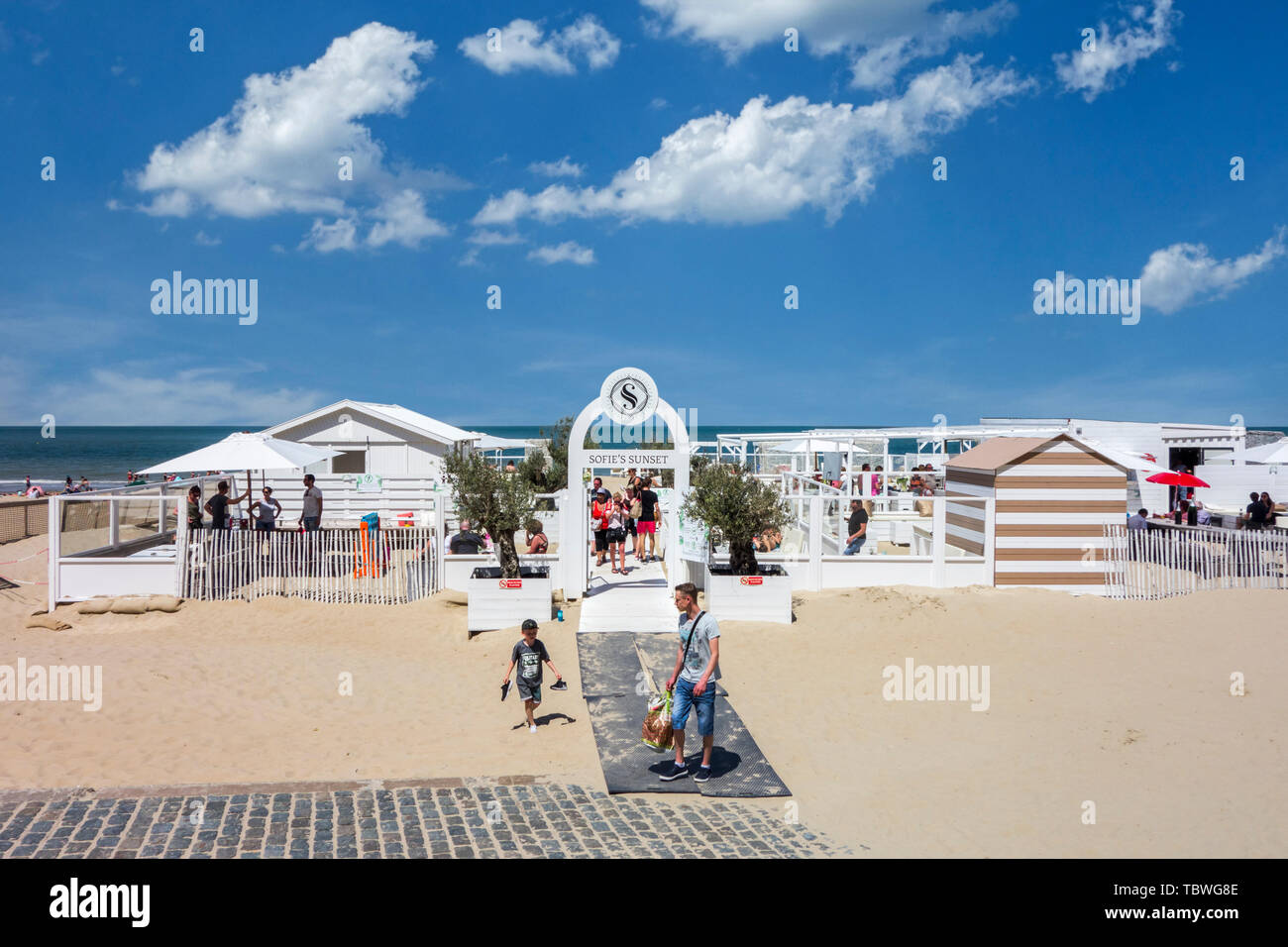 Touristen am Strand Lounge Bar im Badeort an der belgischen Nordseeküste im Sommer, Koksijde/Coxyde, Westflandern, Belgien Stockfoto