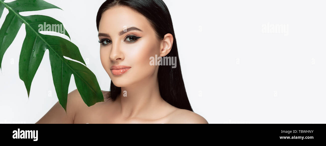 Gegerbt frau gesicht mit perfekten Make-up und gesunde Haut mit tropischen Blatt isoliert auf Weiss. Kosmetik und Gesichtspflege Stockfoto