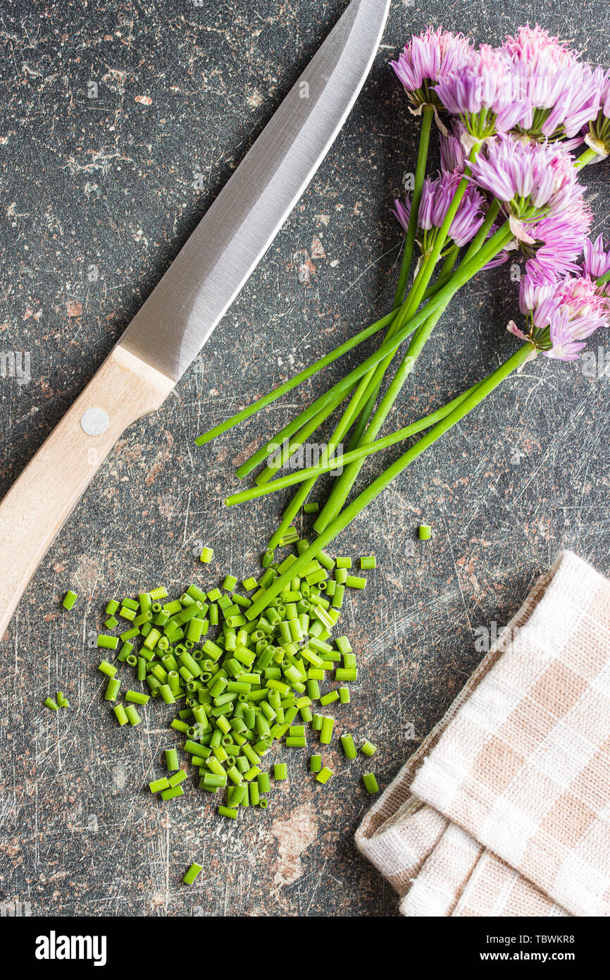 Gehackten Schnittlauch mit Blumen auf alten Küchentisch. Stockfoto