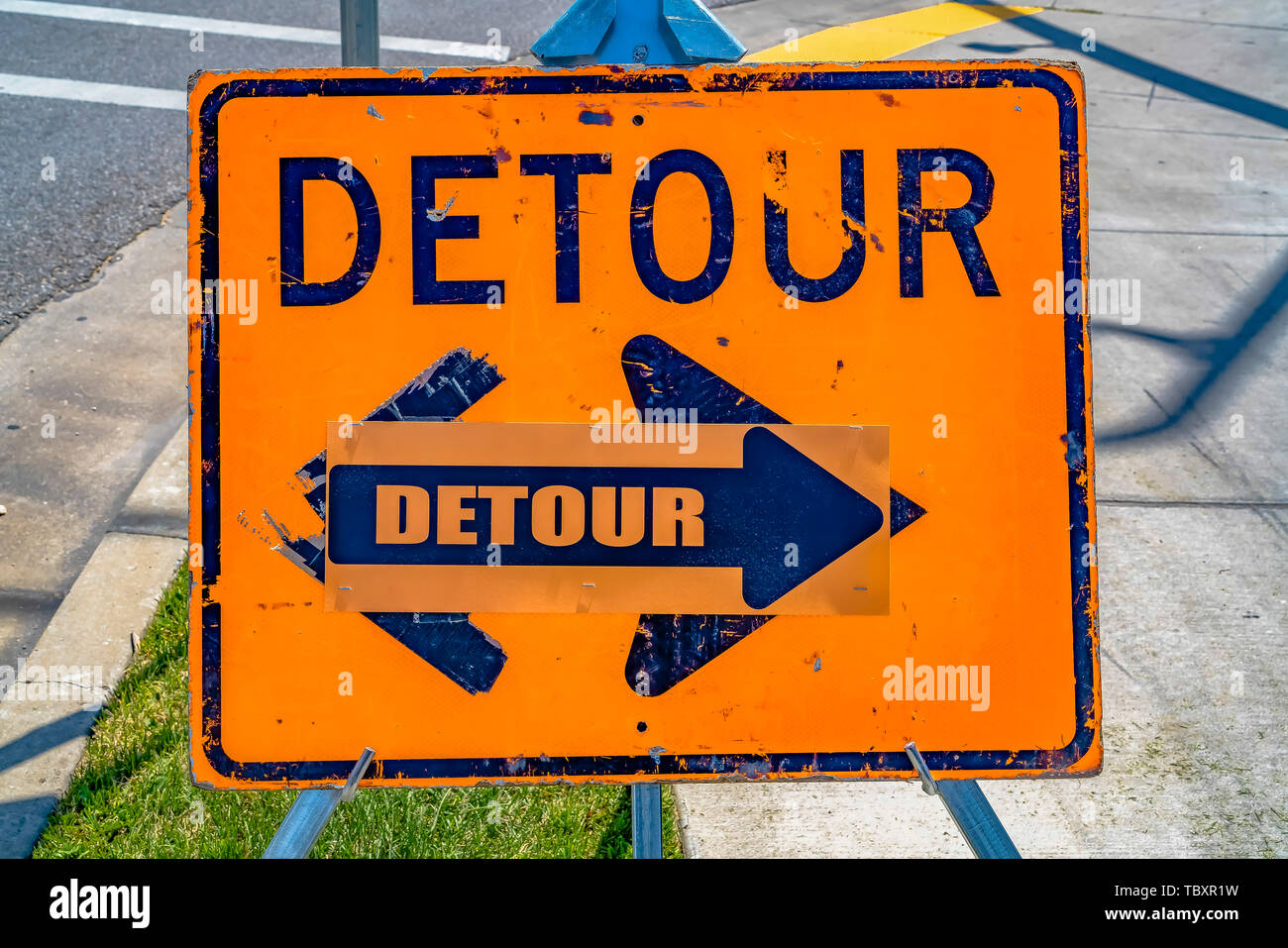 Nahaufnahme eines verwitterten orange und blau Umweg Schild mit Pfeil Stockfoto