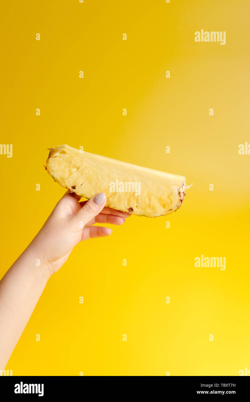 Stück Ananas in der Hand der Frau auf gelbem Hintergrund Stockfoto