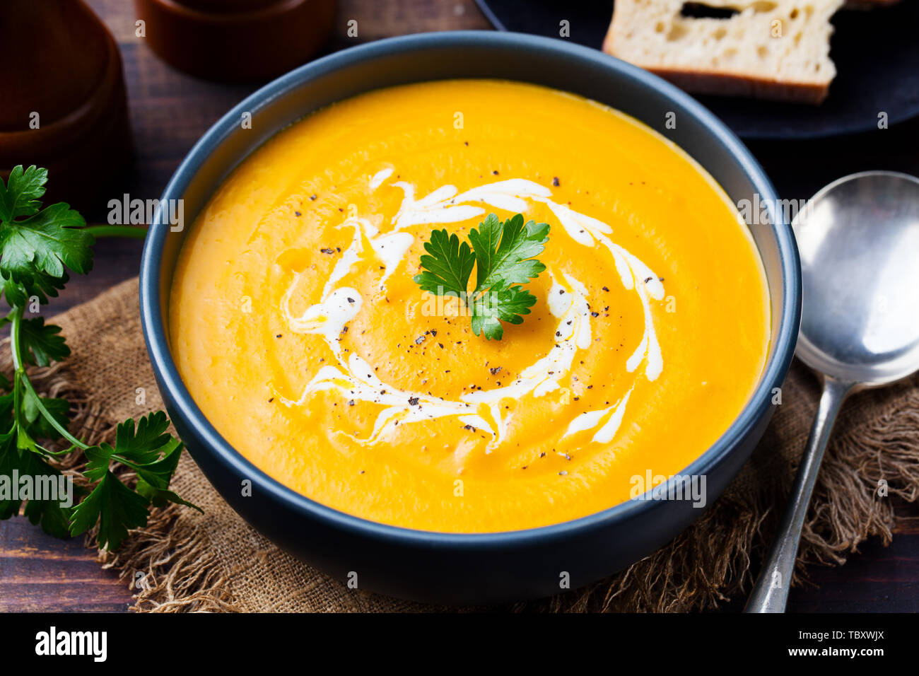 Kürbis und Karotten Suppe, Tadka mit Sahne und Petersilie auf dunklem Hintergrund. Close Up. Stockfoto