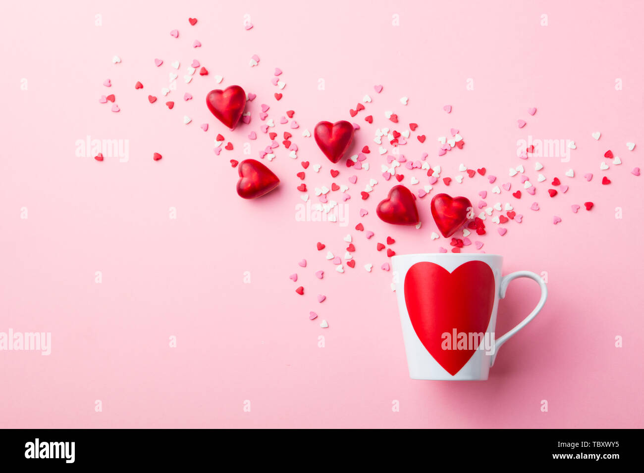 Becher mit Zucker und Schokolade Herzen auf rosa Hintergrund. Flach Komposition. Stockfoto