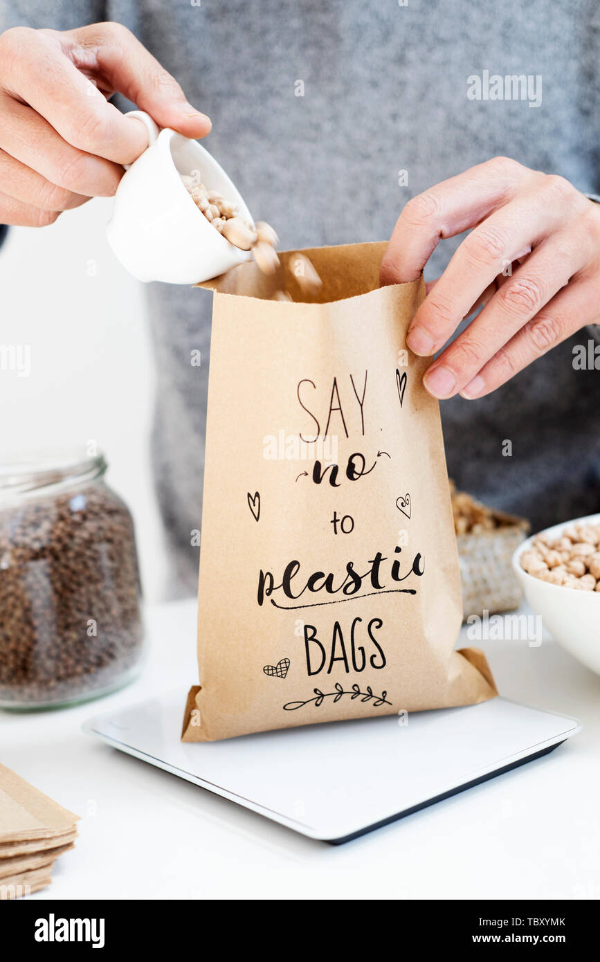 Nahaufnahme von einem kaukasischen Mann einige trockene Kichererbsen auf eine braune Papiertüte, mit dem Text sagen Nein zu Plastiktüten in Es geschrieben, platziert auf einer elektronisch Stockfoto