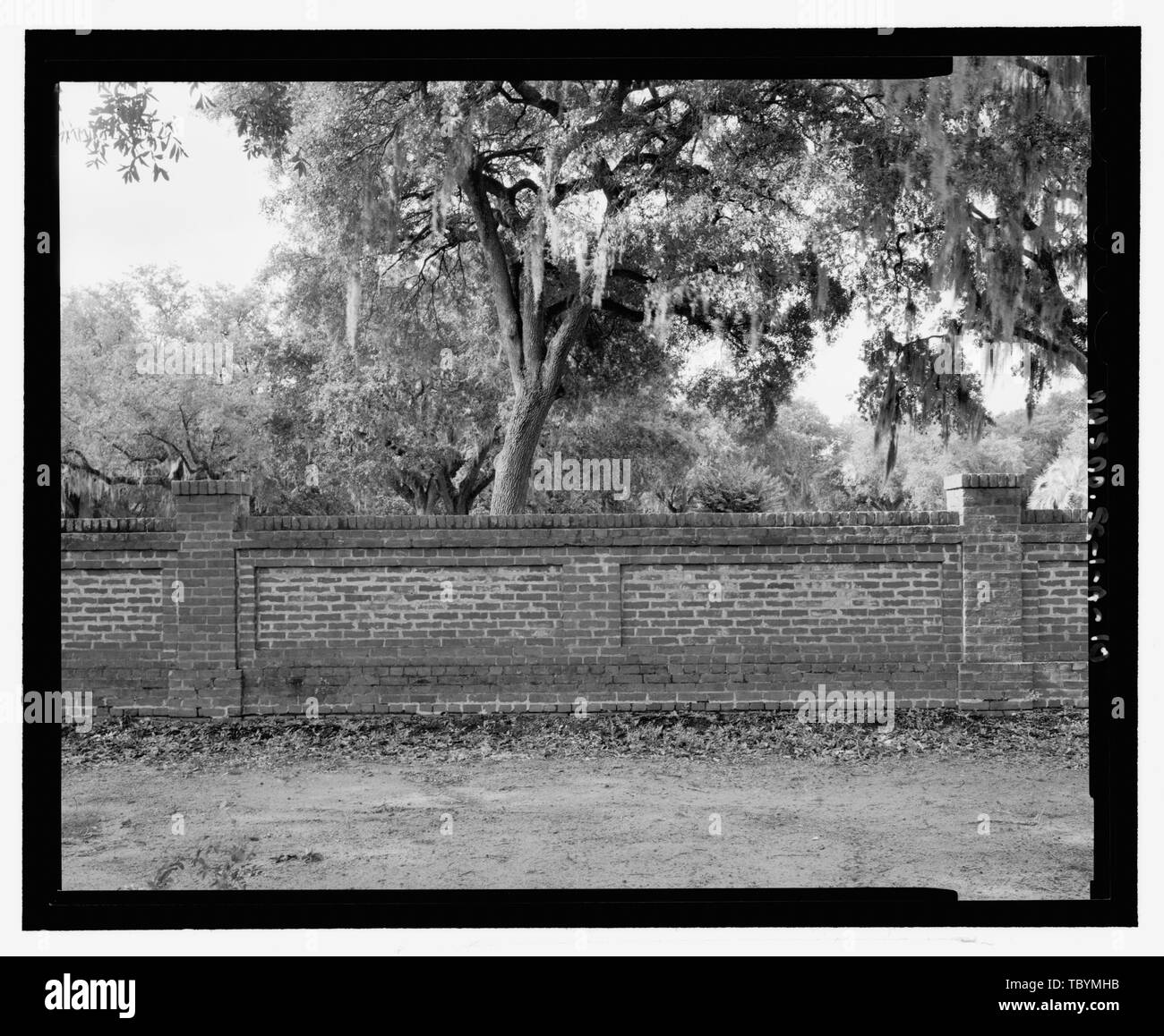 Morgen Blick auf das Äußere des westlichsten Wand Abschnitt auf die Kamera nach Süden entfernt werden. Unbefestigte Straße im Vordergrund Baumkronen im Hintergrund. Beaufort National Cemetery, Wand, 1601 Boundary Street, Beaufort, Beaufort County, SC US-Angelegenheiten der Veteranen der Jaeger Firma, sponsor Jaeger, Dale, Landschaftsarchitekt Hetzen, Lukas, Landschaftsarchitekt LaBrie, Brian, Historiker Stockfoto